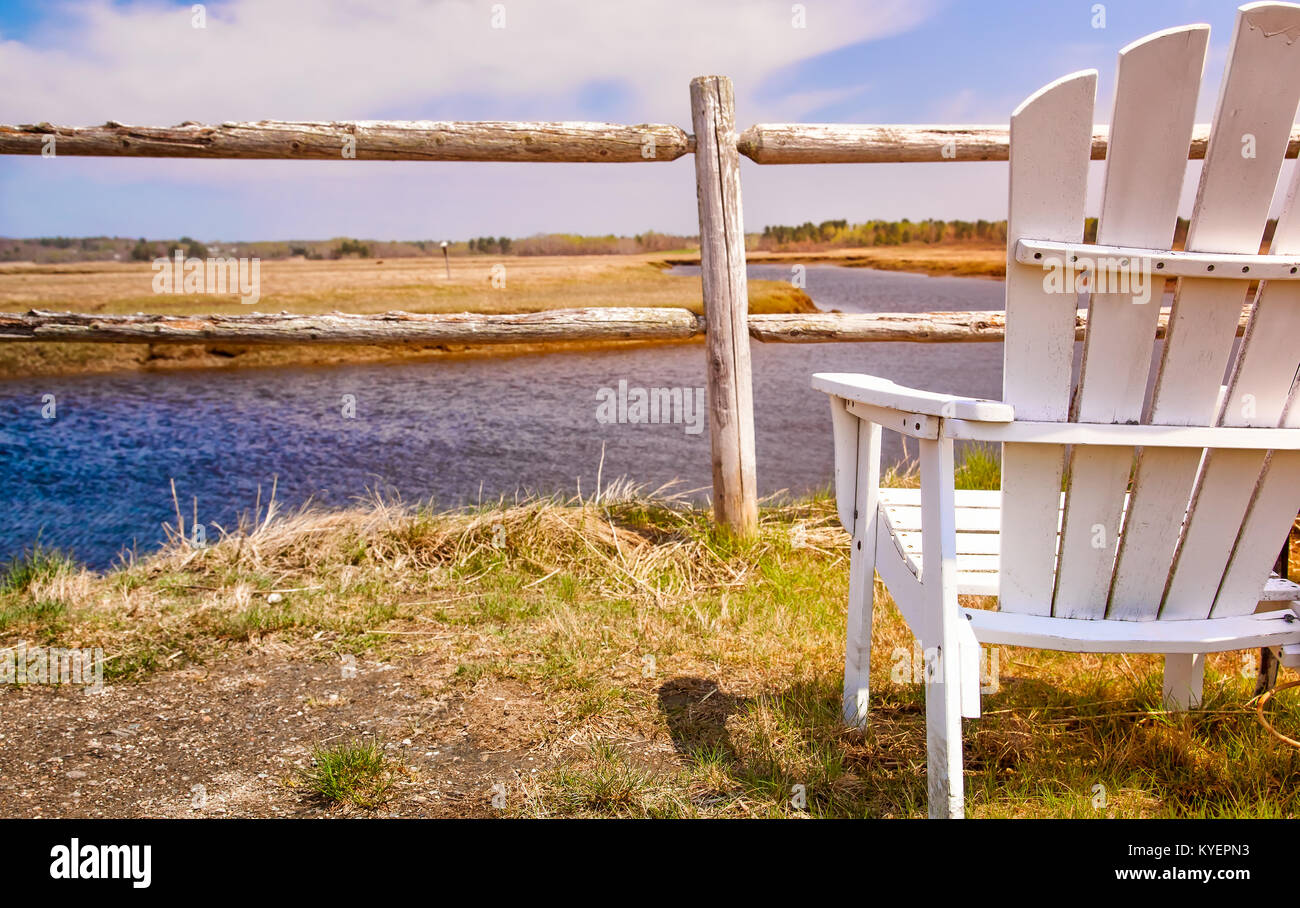 White Adirondack chair close up facing a view of marshes in Maine. Beautiful landscape. Stock Photo