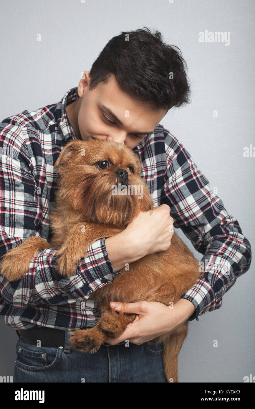 Closeup portrait handsome young hipster man, kissing his good friend red dog isolated light background. Positive human emotions, facial expression, feelings Stock Photo