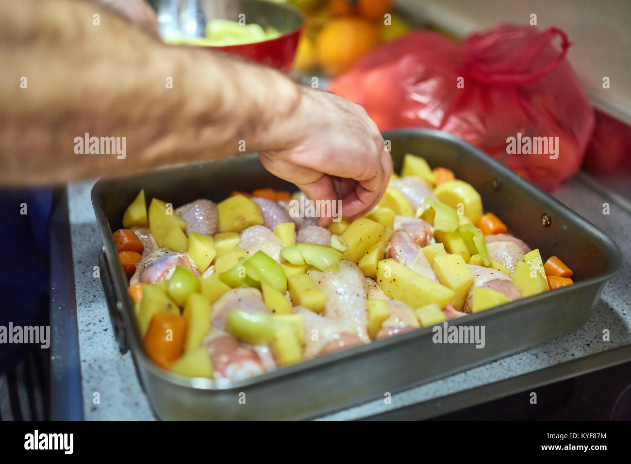 Hands of a mature man cooking chicken drums in an oven tray Stock Photo