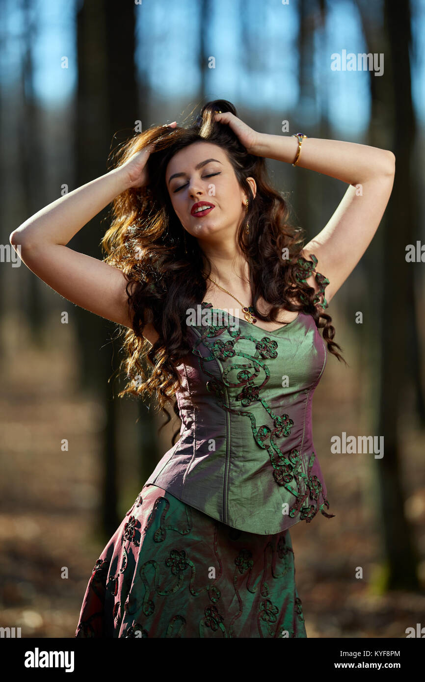 Closeup portrait of a beautiful young brunette in green dress outdoor ...