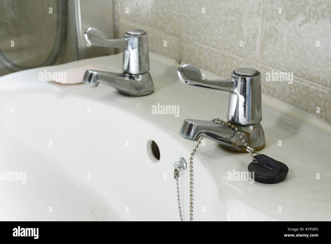 Close up detail of a domestic hand basin in white ceramic with silver taps with levers Stock Photo