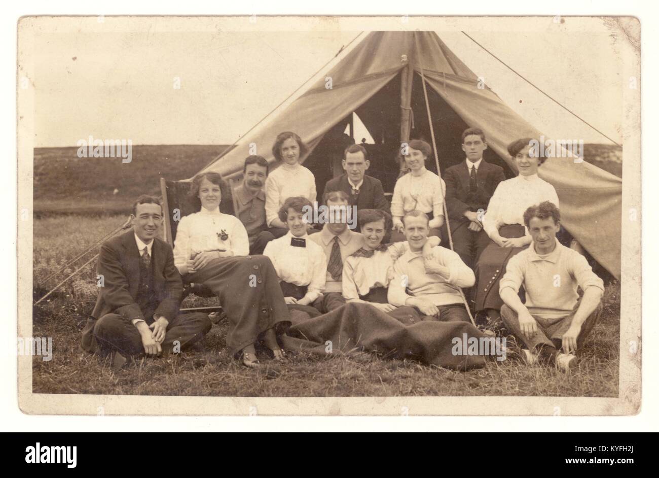 Early1900s postcard of a group of men and women camping under canvas, relaxing and enjoying themselves outside a canvas tent, probably just before the Great War, circa 1913, U.K Stock Photo