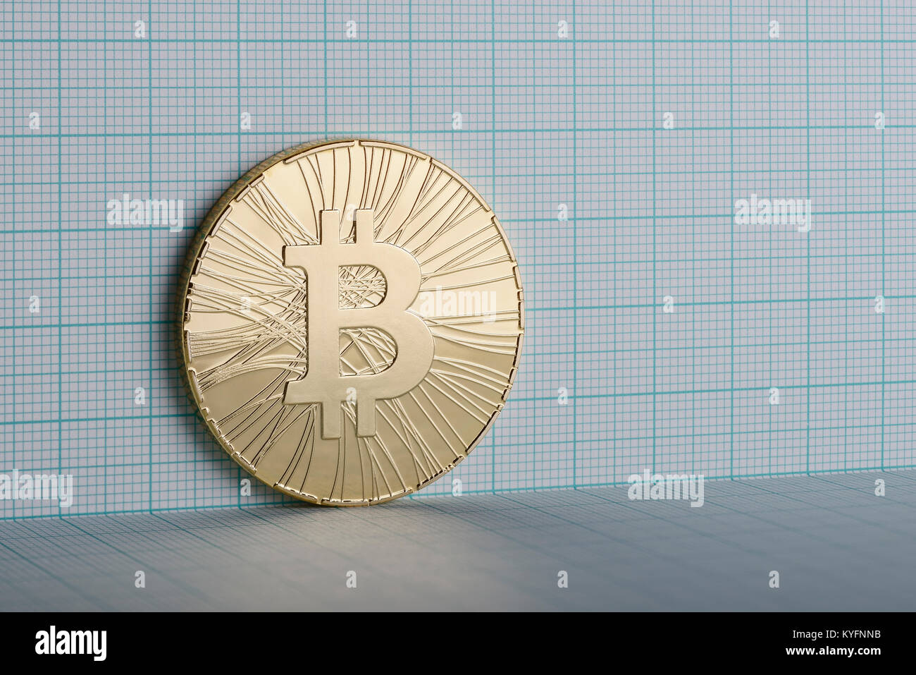 Gold coloured Bitcoin coin on graph paper Stock Photo
