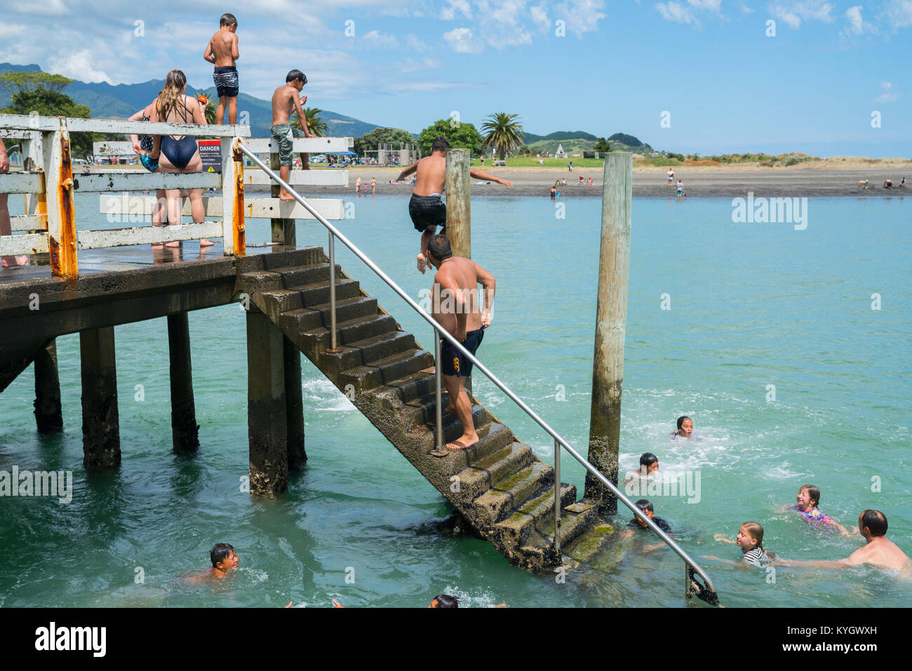 RAGLAN NEW ZEALAND - JANUARY 14, 2018; Summer fun in Raglan mostly local Maori boys jumping from the small wharf in small New Zealand town on North Is Stock Photo