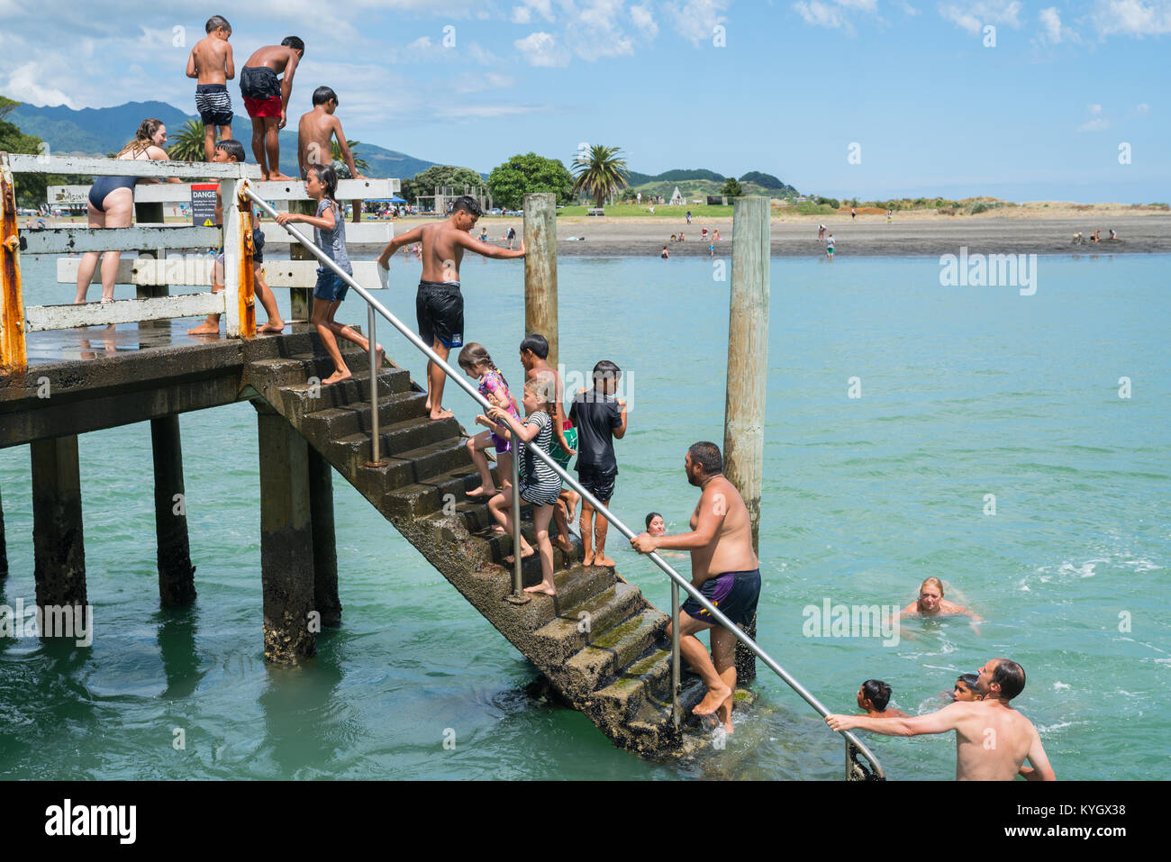 RAGLAN NEW ZEALAND - JANUARY 14, 2018; Summer fun in Raglan mostly local Maori boys jumping from the small wharf in small New Zealand town on North Is Stock Photo