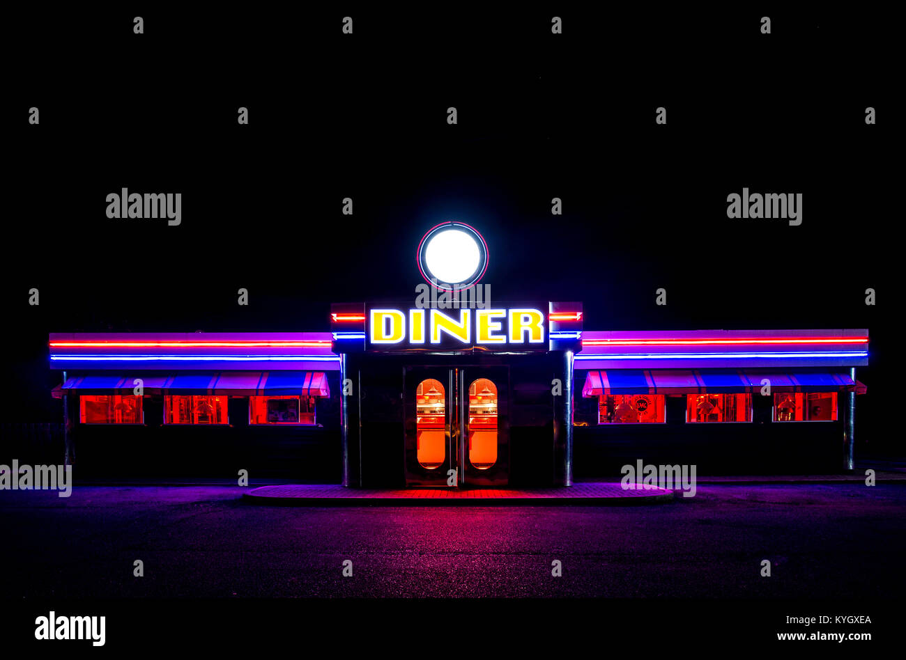 A traditional American Diner at night with a large sign and clorful luminous, fluourescent and neon lighting that glows in the dark. Stock Photo
