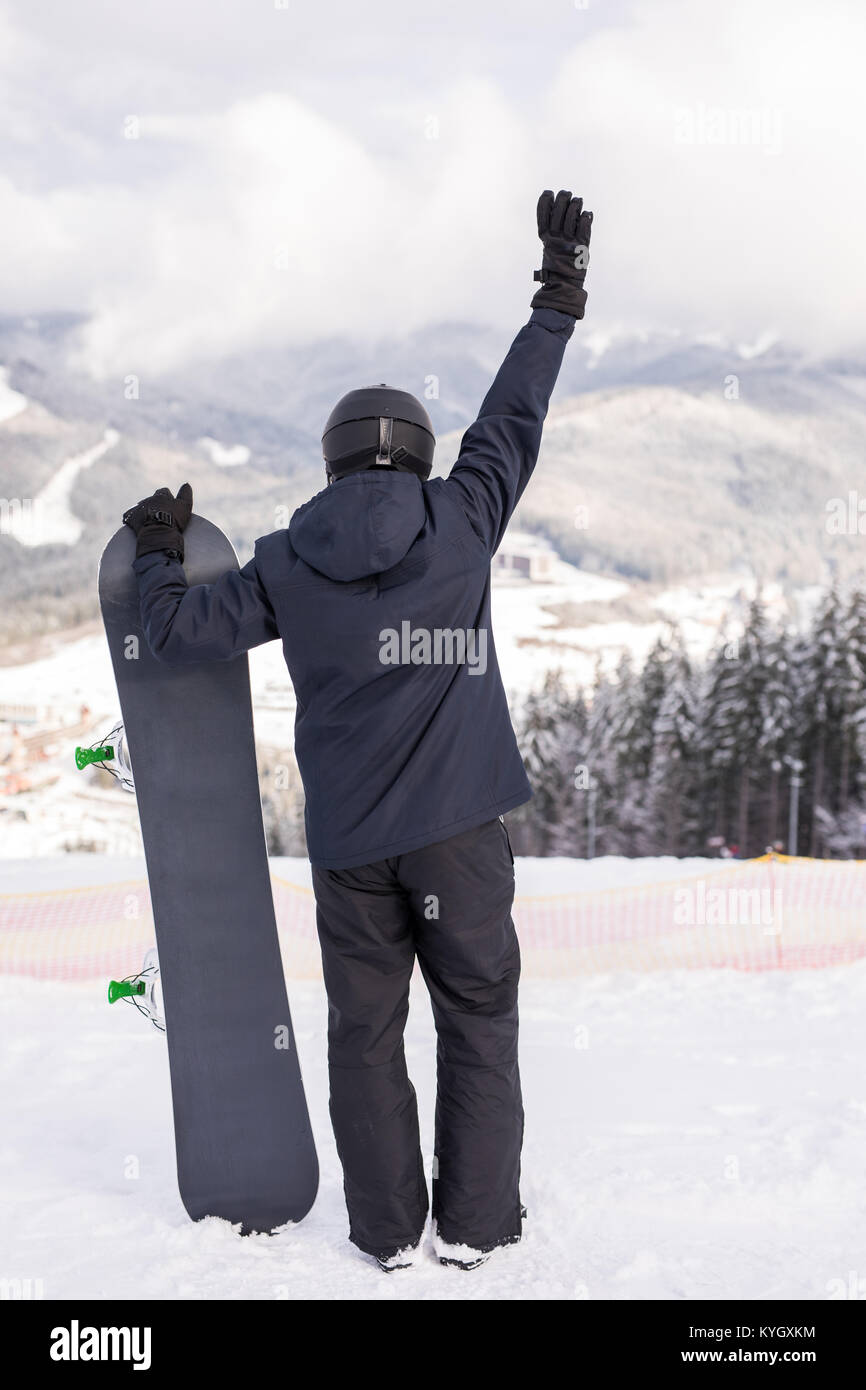 Rear view of sportsman with snowboard watching the nature Stock Photo ...