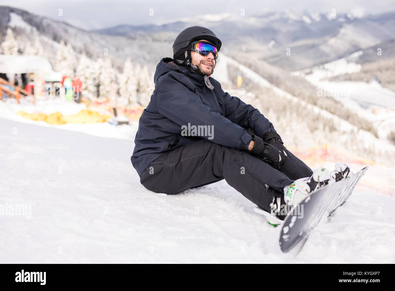 Snowboarder sitting on a ski slope on hill Stock Photo