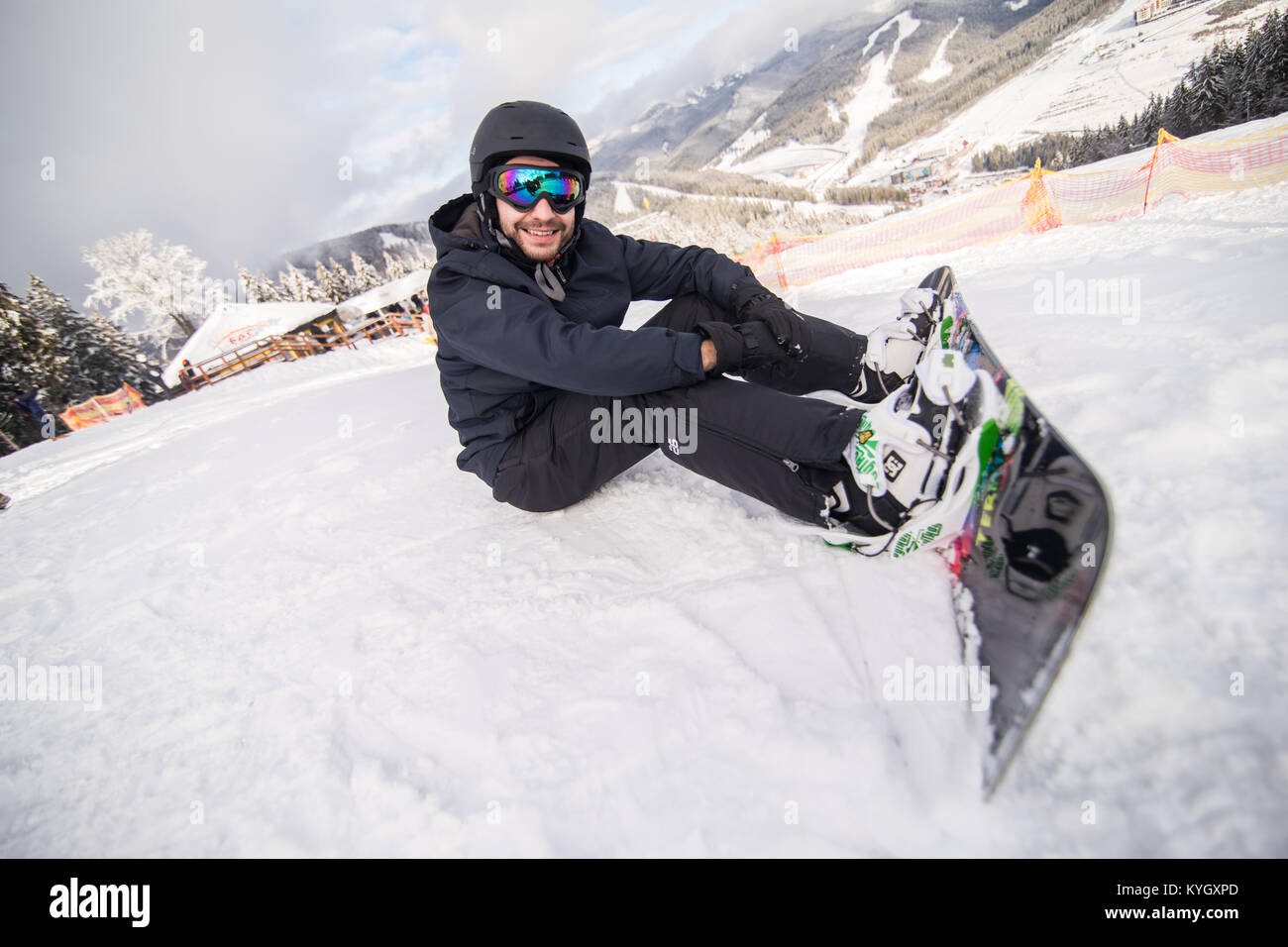 Snowboarder sitting on a ski slope on hill Stock Photo