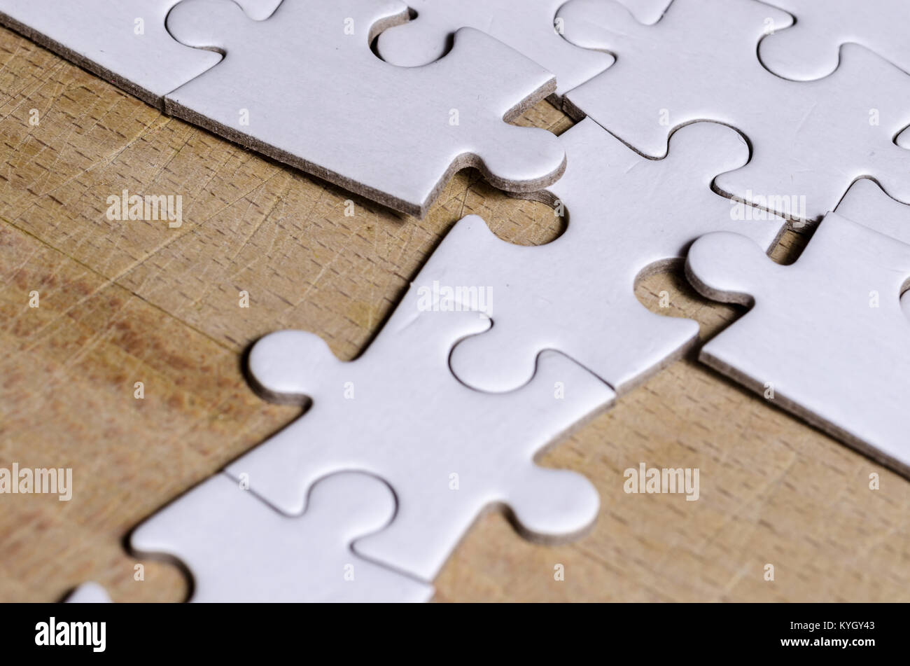 white jigsaw/puzzle with a row in wrong position, over  wooden table background, symbol of problem solving and new vision Stock Photo
