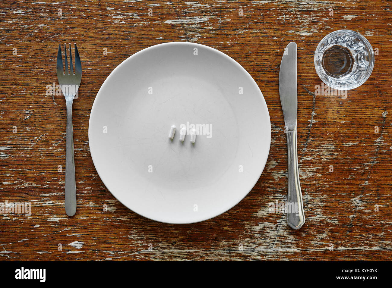 three pills on plate knife and fork Stock Photo