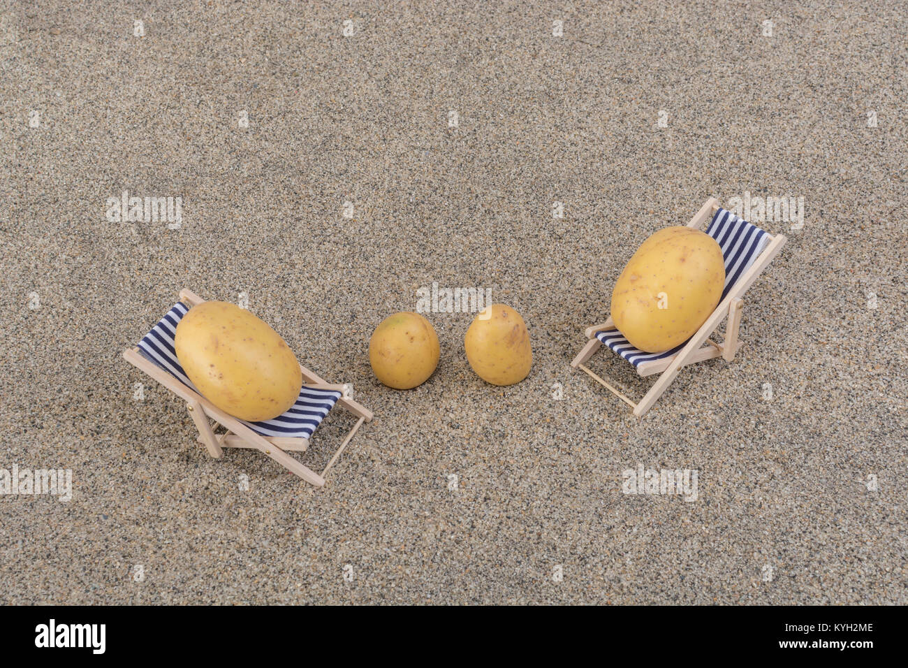 New potato on toy deckchair on sand as visual metaphor for concept of