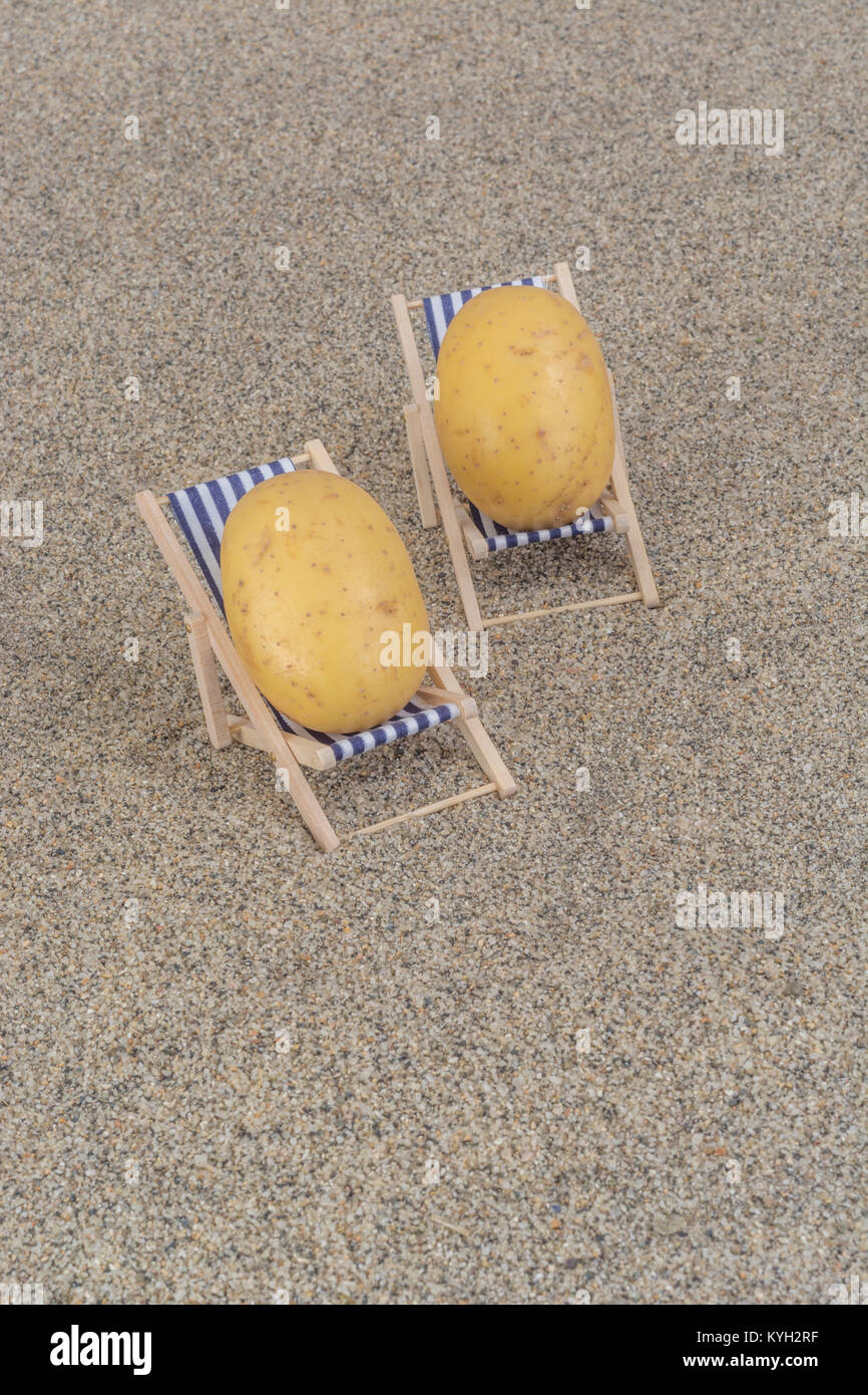New potatoes on toy deckchair on sand as visual metaphor for concept