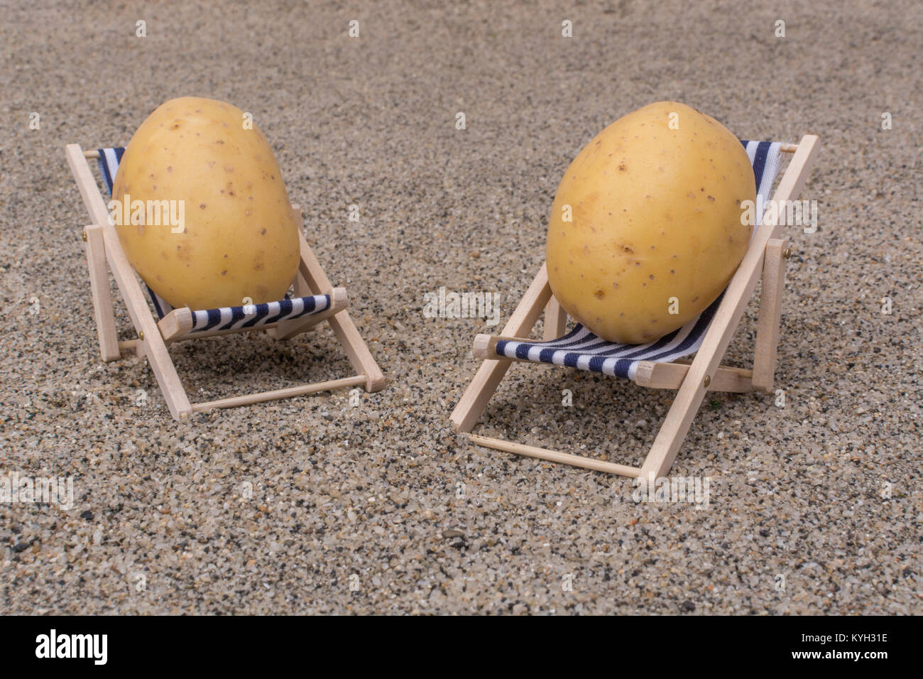 New potatoes on toy deckchair on sand as visual metaphor for concept