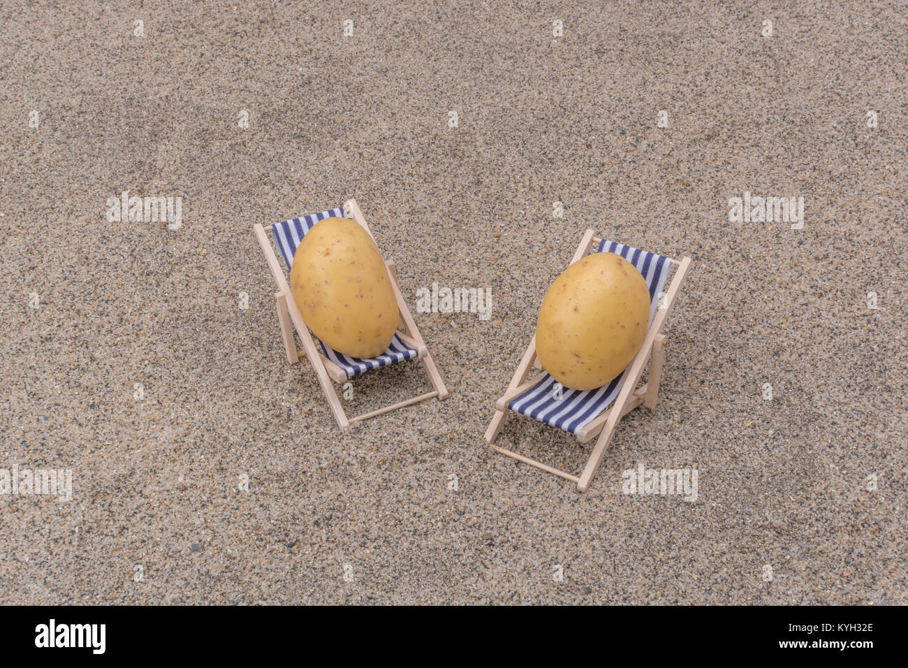 New potatoes on toy deckchair on sand as visual metaphor for concept