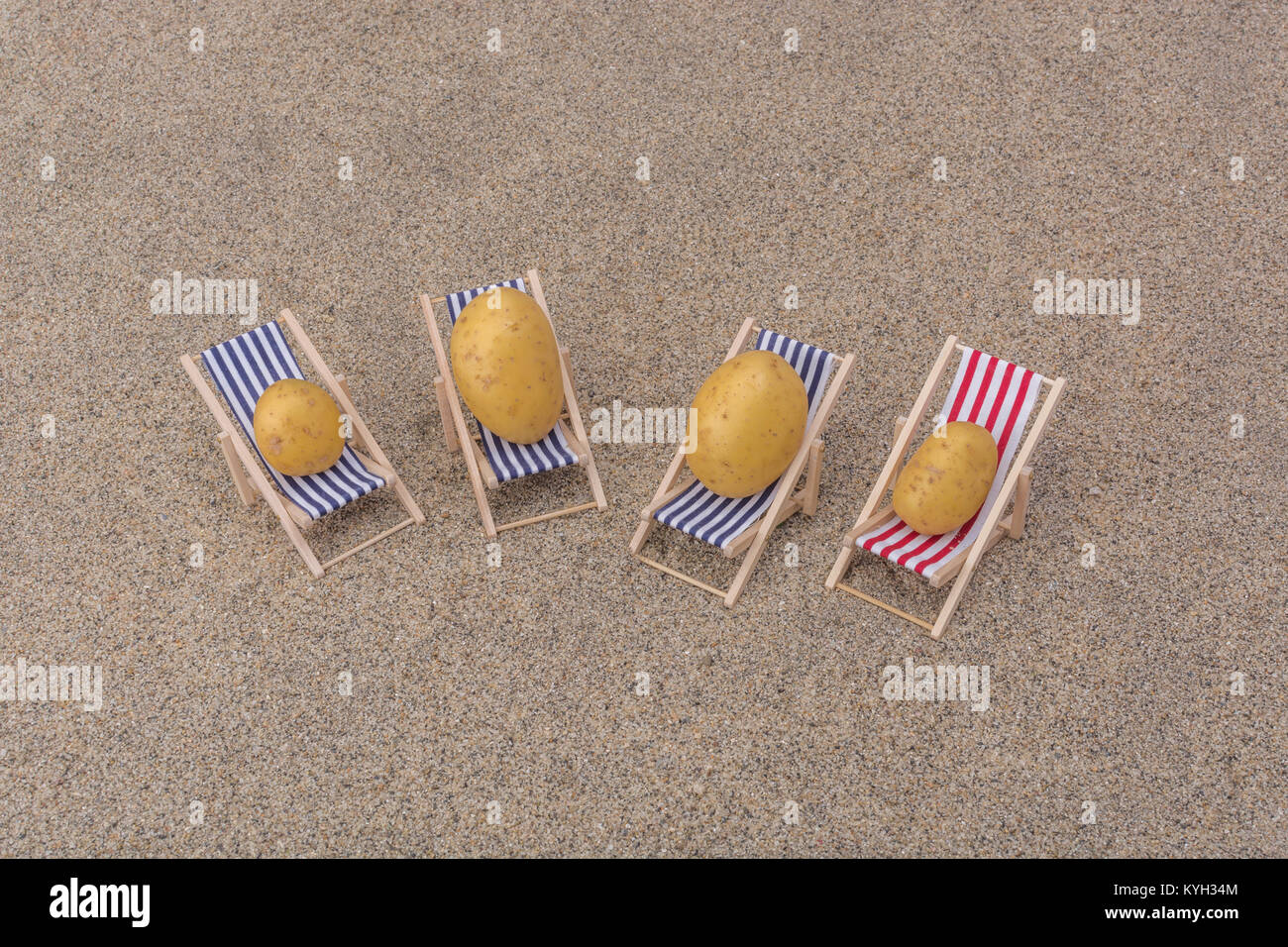 New potato on toy deckchair on sand as visual metaphor for concept of
