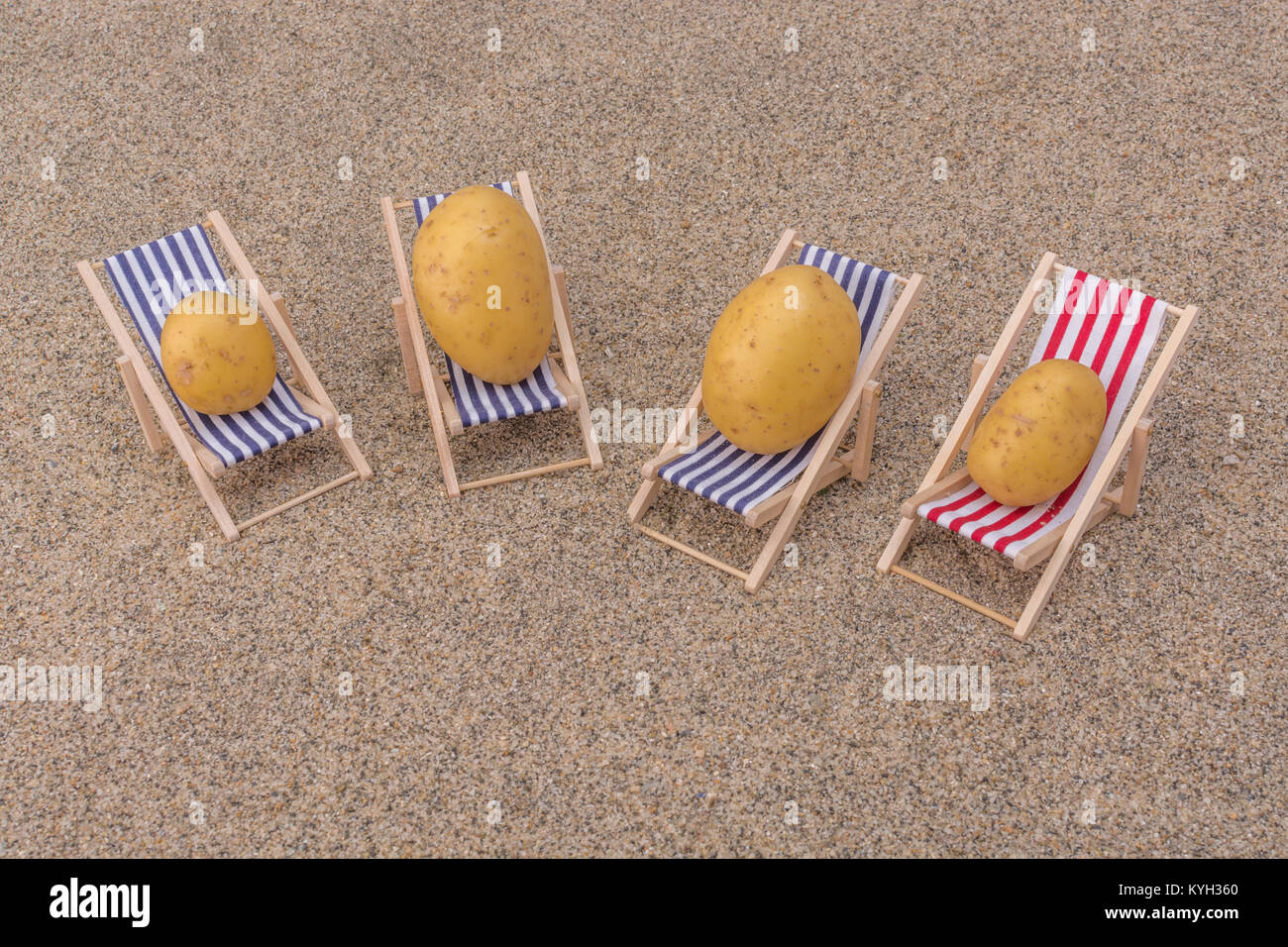 New potato on toy deckchair on sand as visual metaphor for concept of