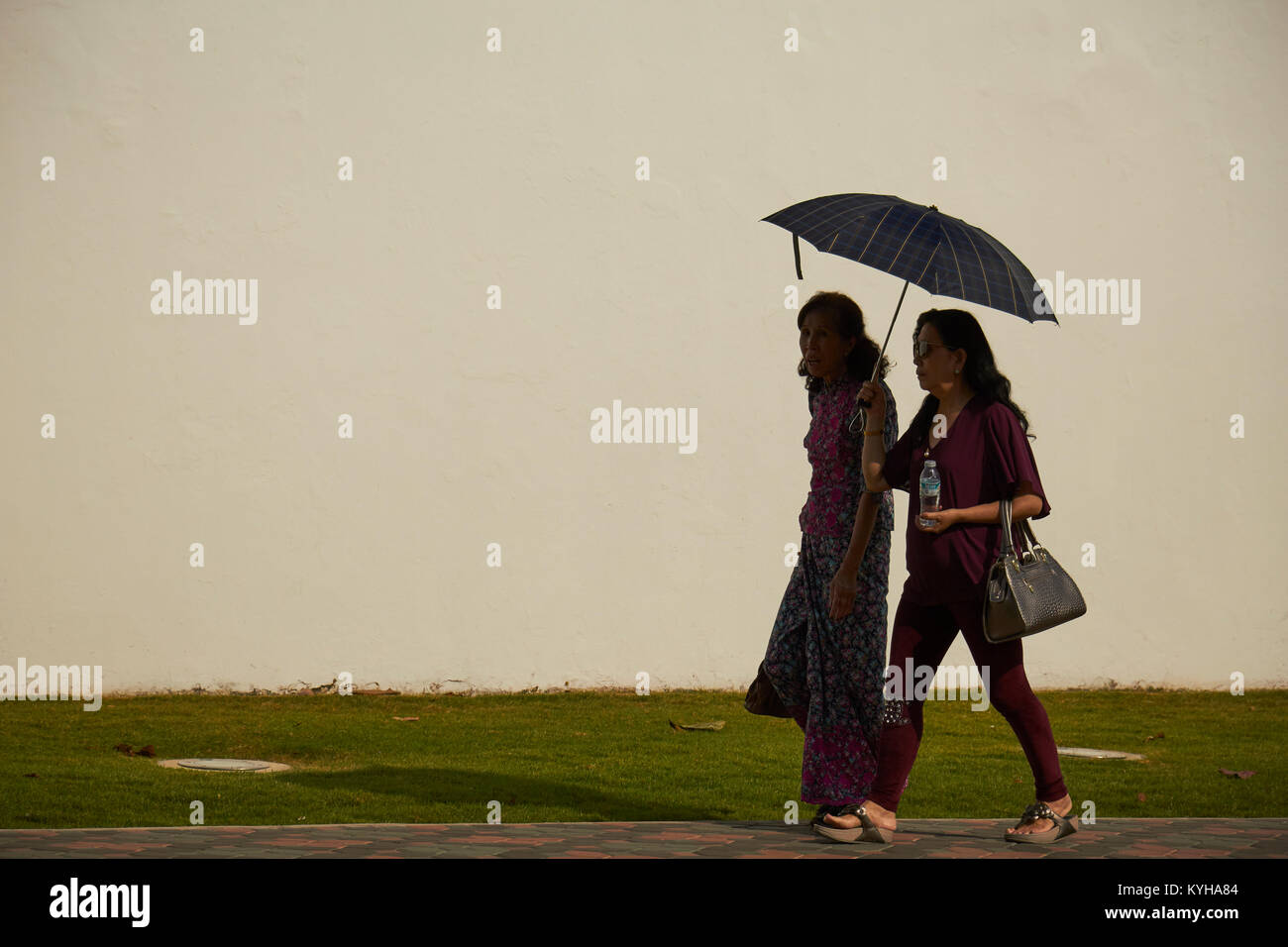 Women walking on a Bangkok street shaded by an umbrella Stock Photo