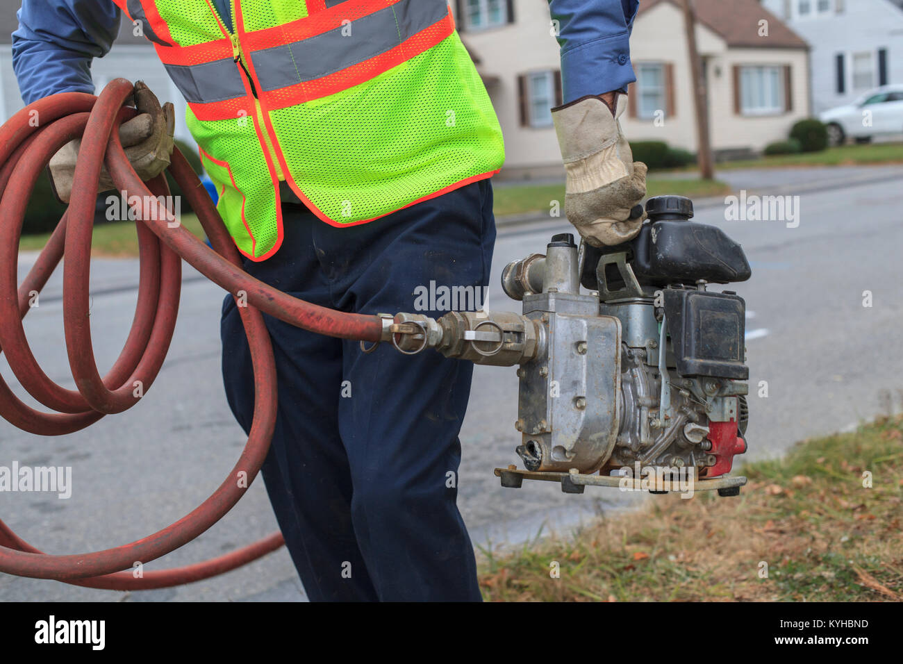 Water department technician carrying gasoline powered pump for flushing hydrants Stock Photo