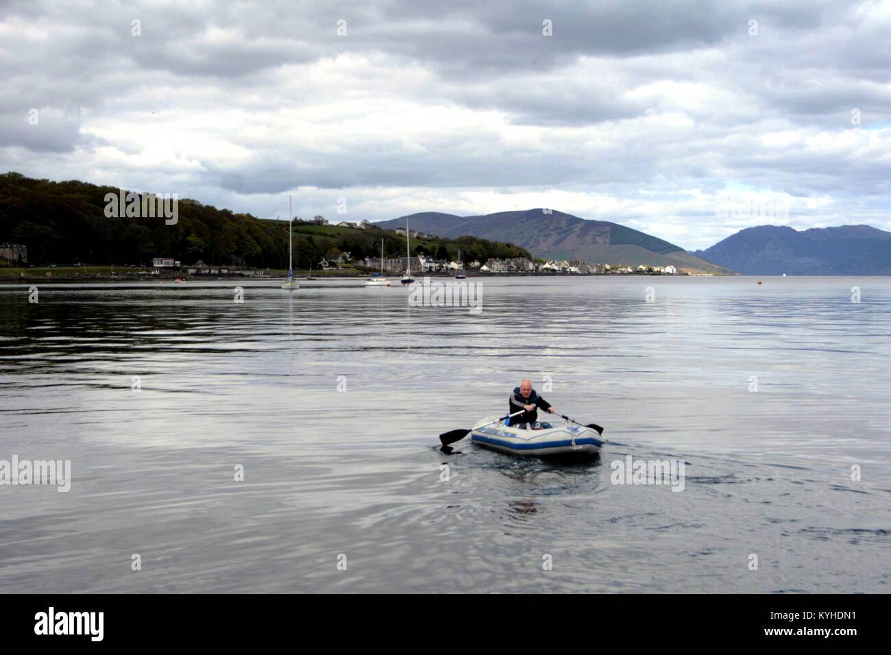 man in a dinghy dingy or rubber raft boat in the harbour Rothesay, United Kingdom Stock Photo
