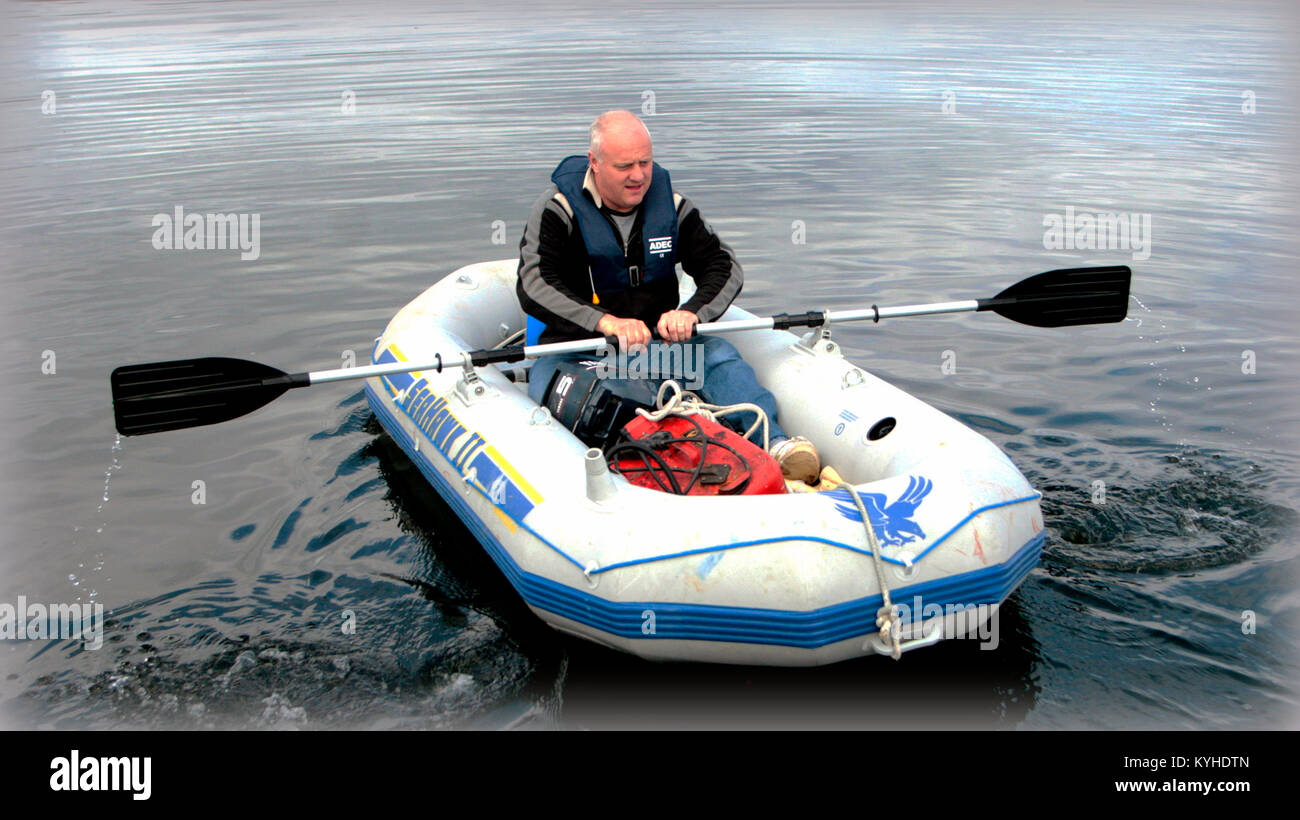 man in a dinghy dingy or rubber raft boat in the harbour Rothesay, United Kingdom Stock Photo
