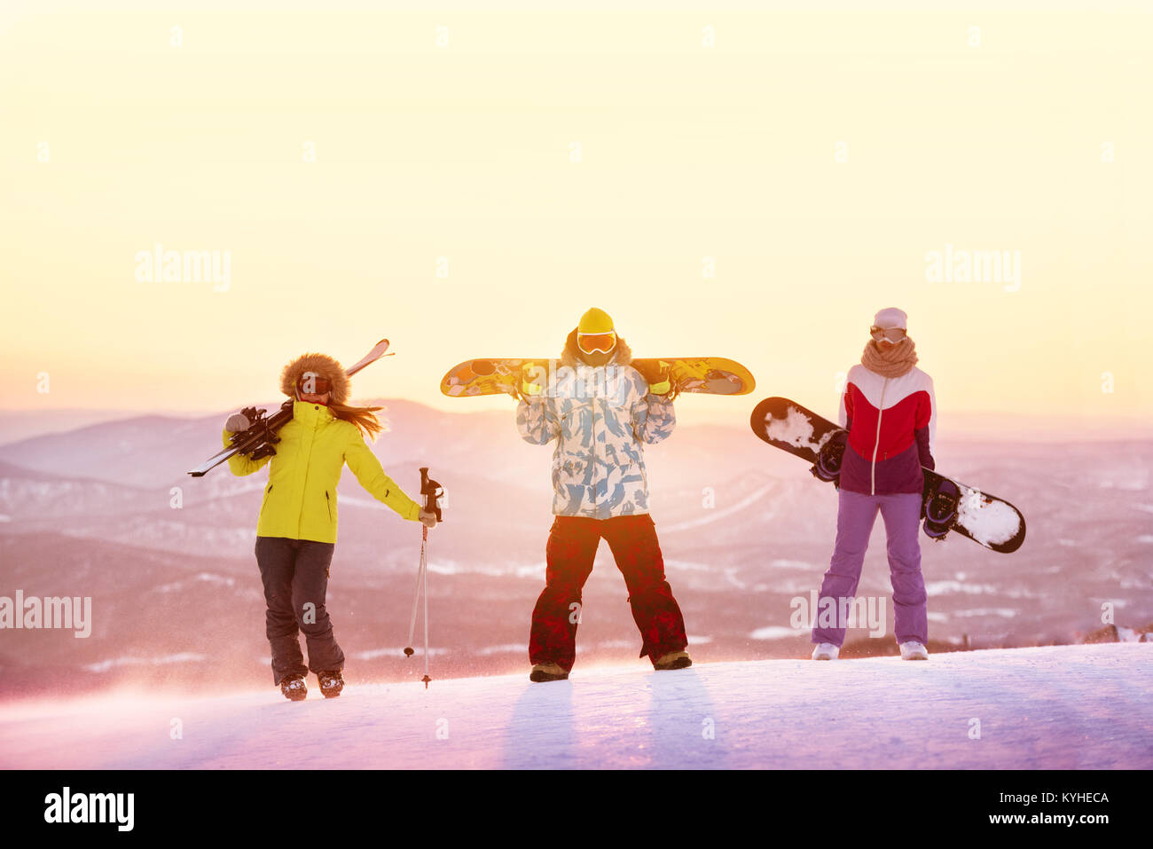 Ski or snowboard concept with three friends against sunset Stock Photo