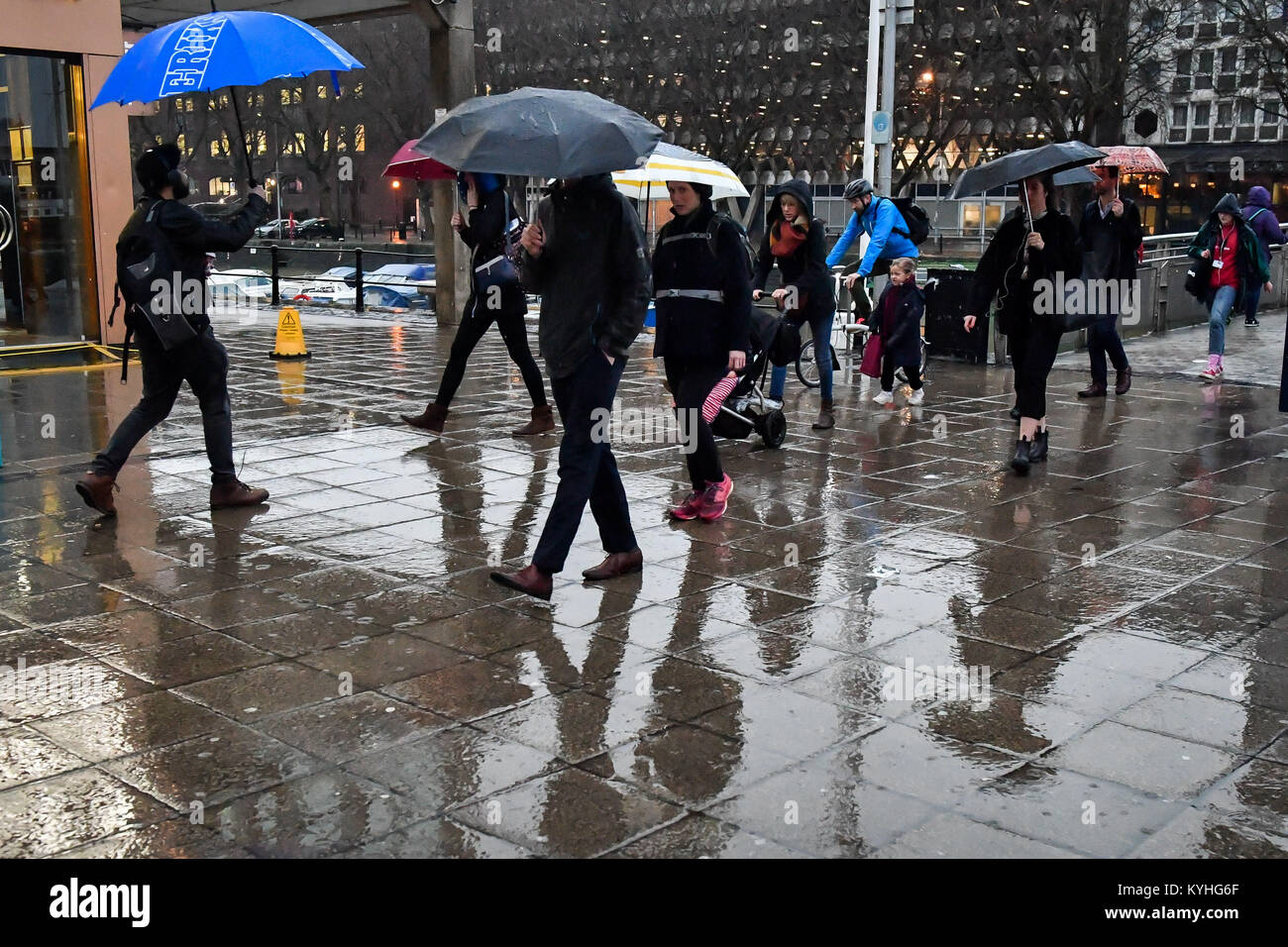 People shelter under umbrellas in pouring rain as they commute to work
