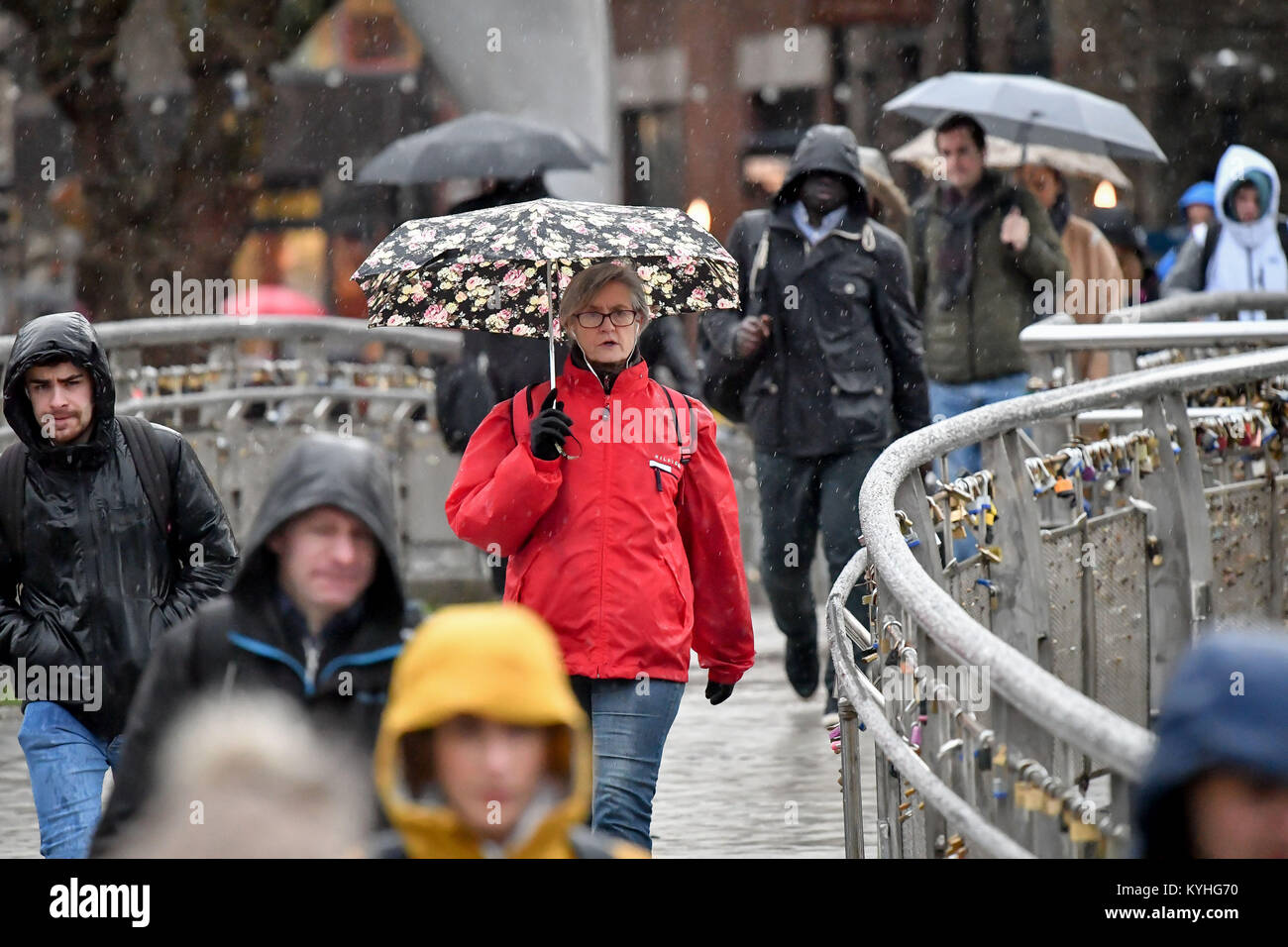 People shelter under umbrellas in pouring rain as they commute to work
