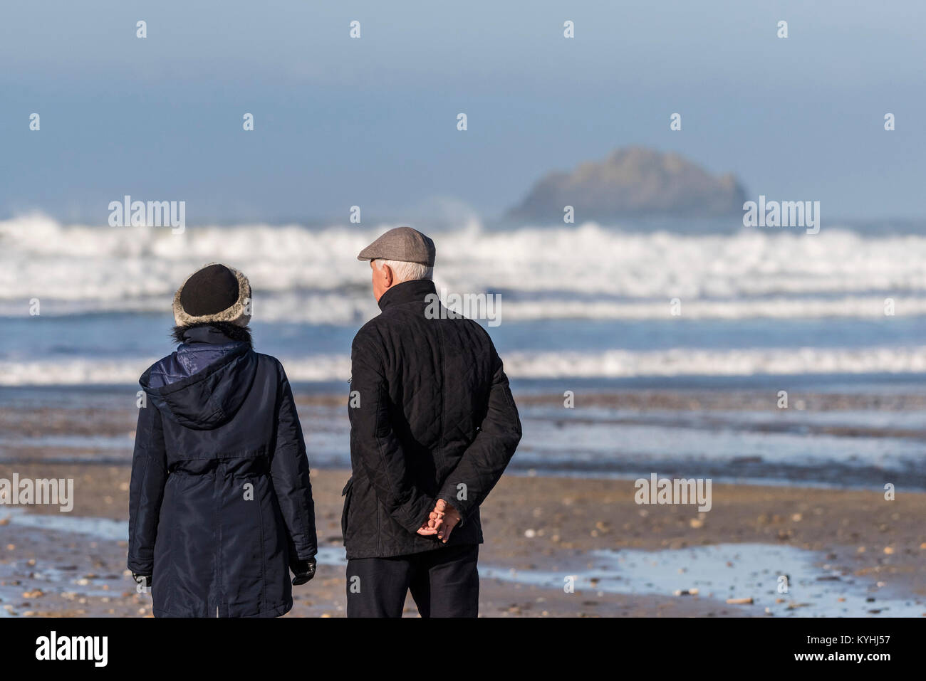 Two people couple standing on a beach enjoying the view. Stock Photo