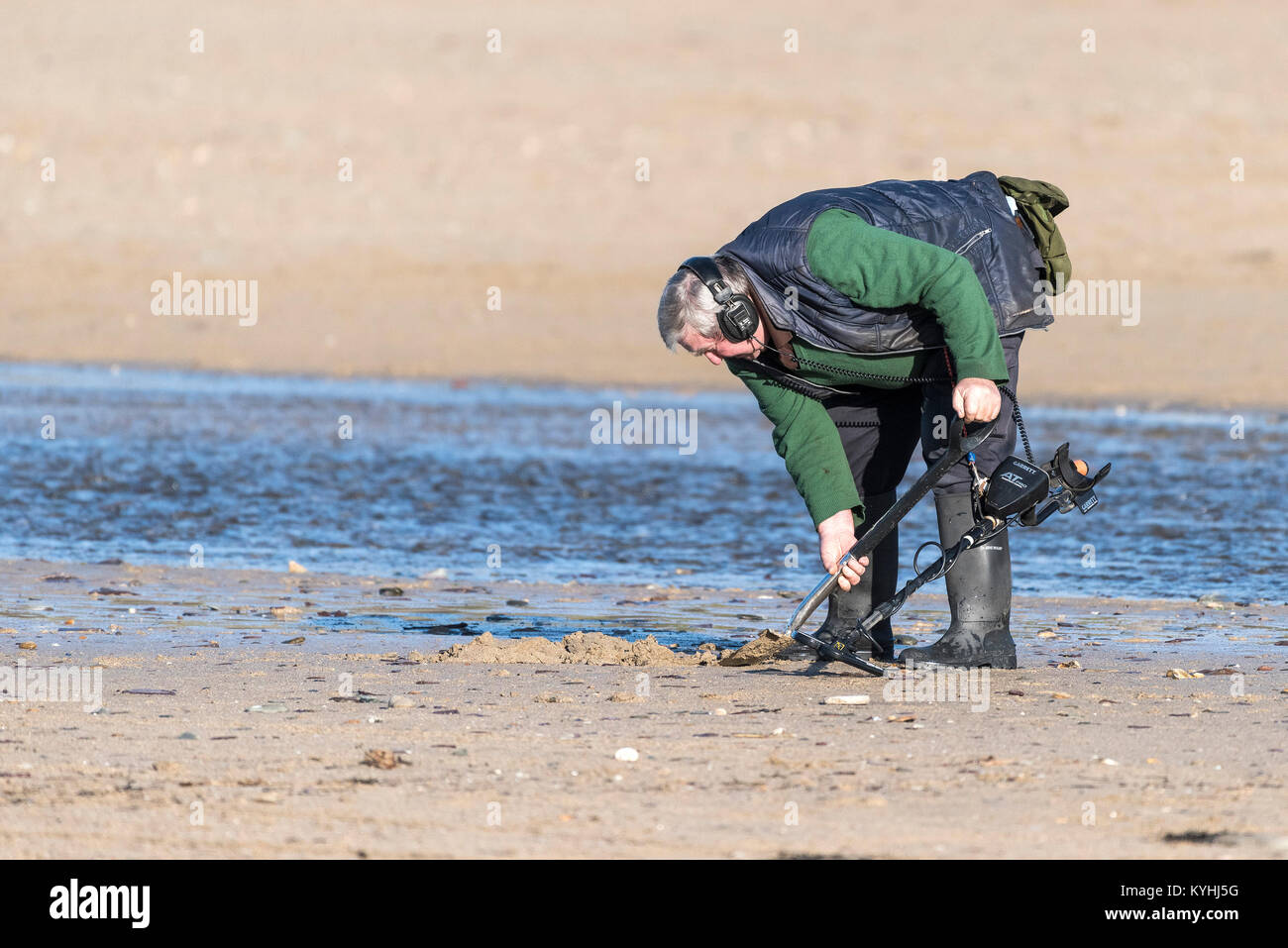 Metal detecting - a metal detectorist searching on Polzeath Beach on the North Cornwall Coast. Stock Photo