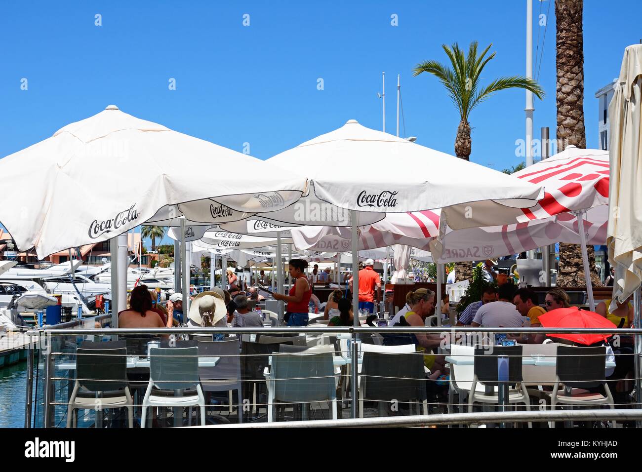 Tourists relaxing at a waterfront restaurant with yachts to the left hand side, Vilamoura, Algarve, Portugal, Europe. Stock Photo
