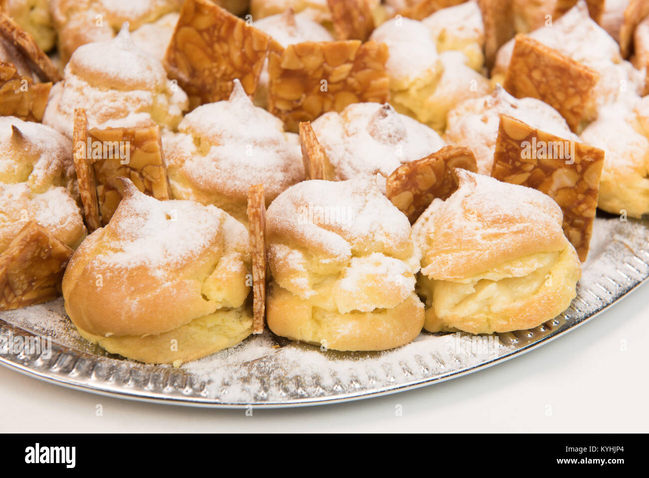 Cream puffs filled vanilla custard and dusted with icing on a plat and ...