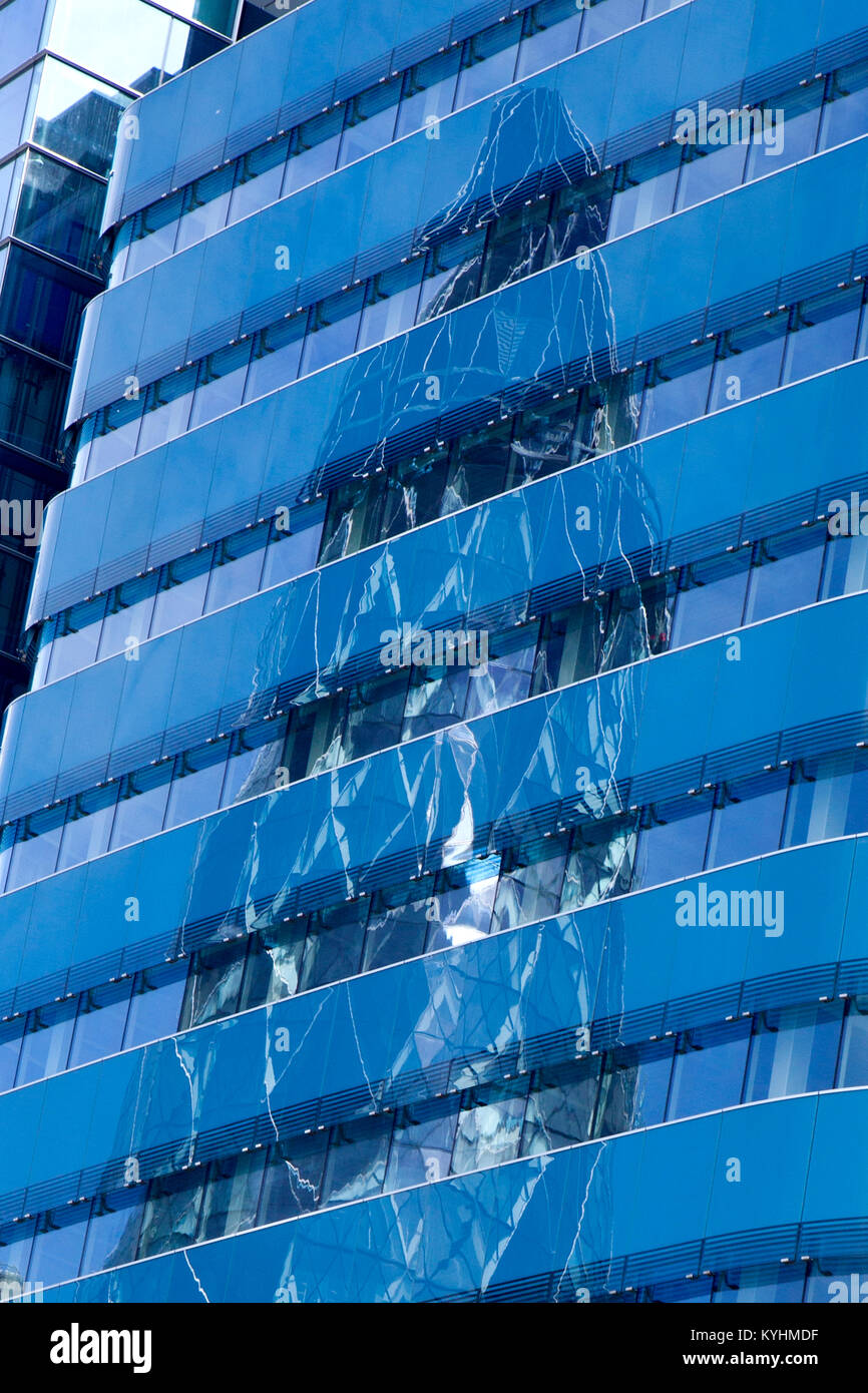 A reflection of the Gherkin 30 St Mary's Axe In a blue glass building in London Stock Photo