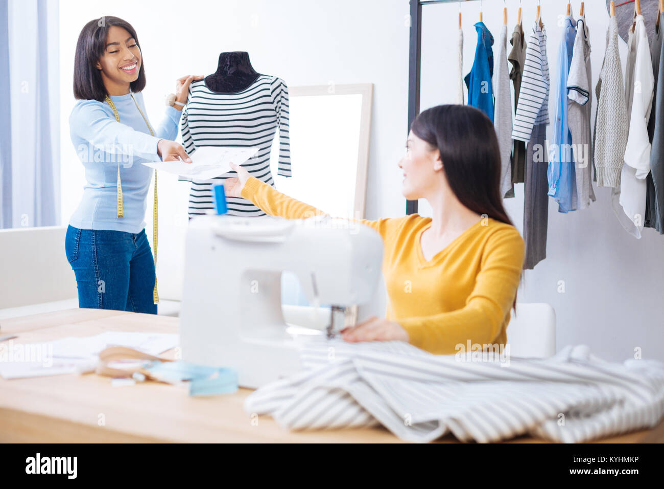 Positive tailor giving her colleague a sketch of a new dress Stock ...