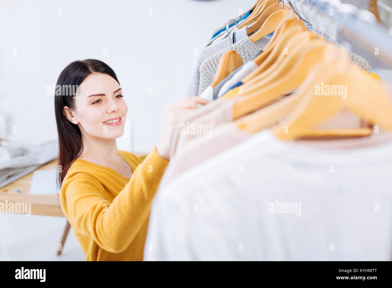 Positive young woman smiling while looking at the new clothes Stock Photo