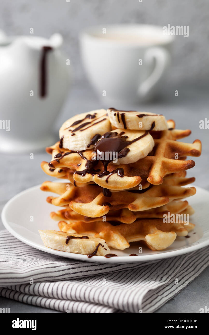 Waffles with banana and chocolate sauce on a gray concrete background ...