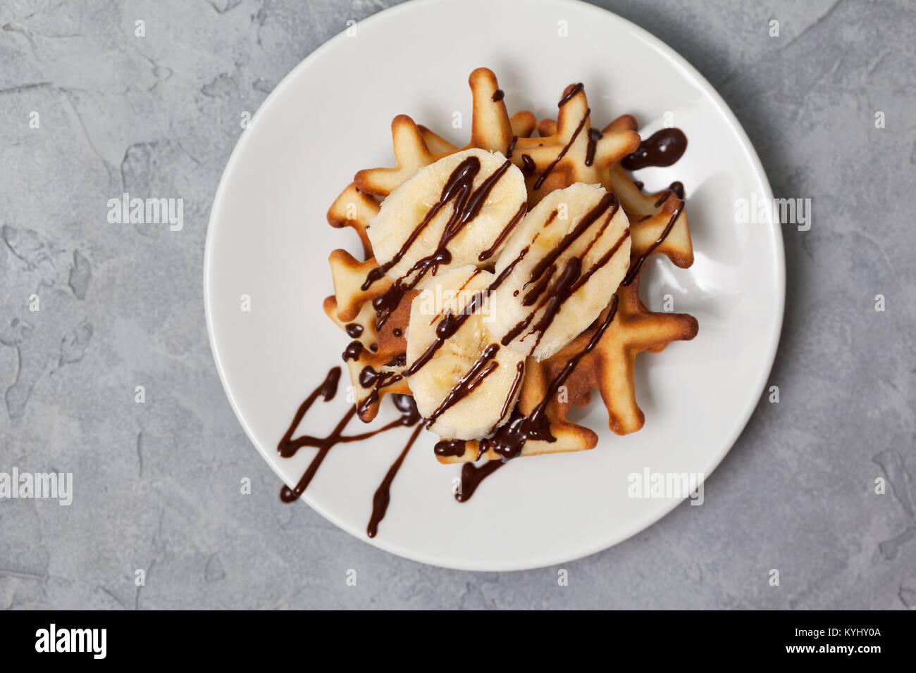 Waffles with banana and chocolate sauce on a gray concrete background ...