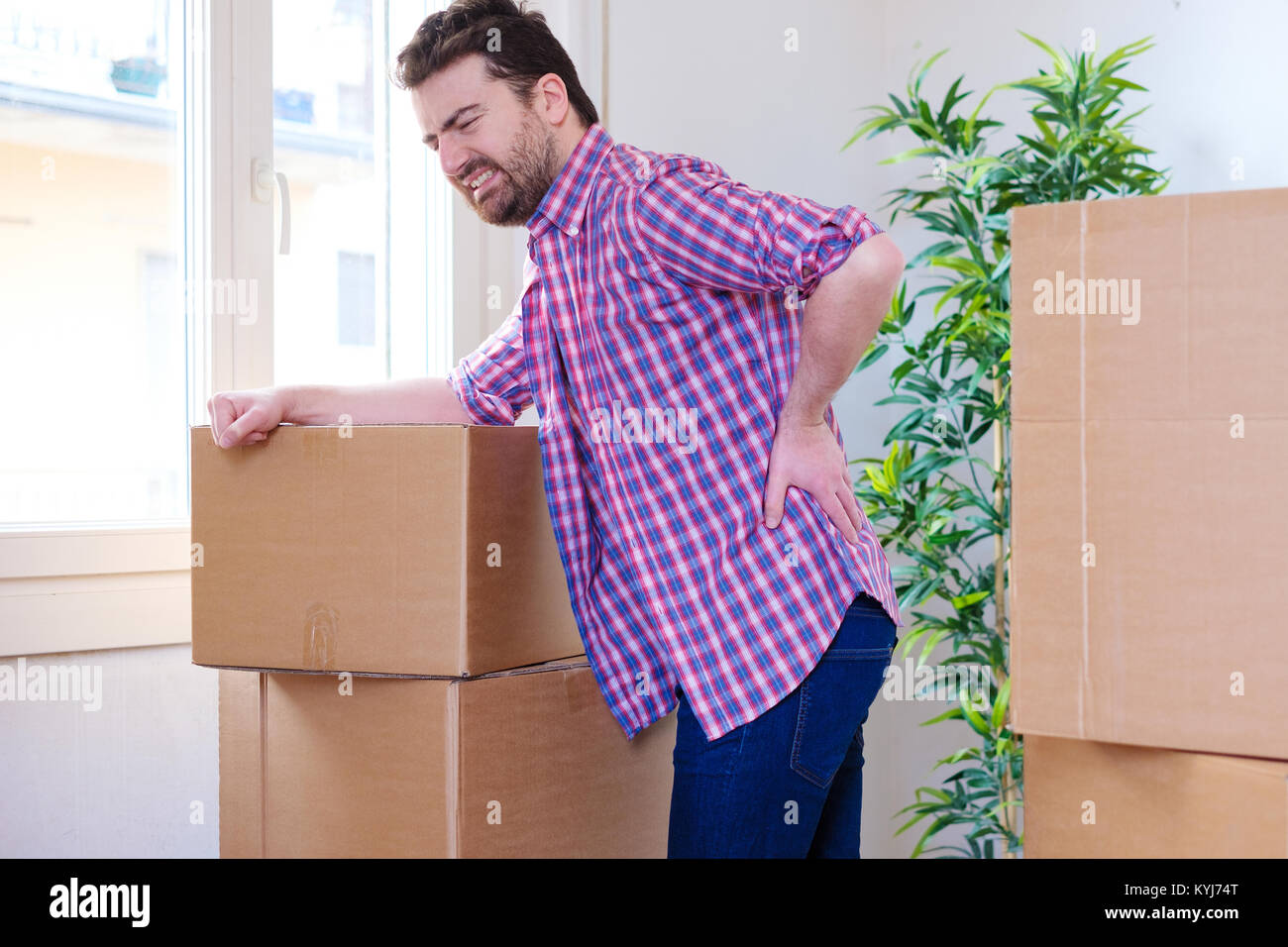 Man moving boxes and feeling back pain because heavy weight Stock Photo