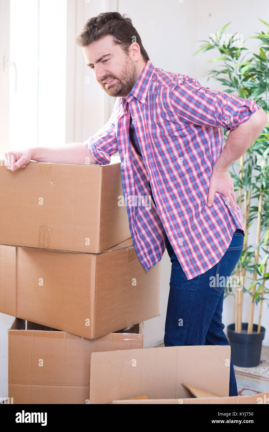 Man moving boxes and feeling back pain because heavy weight Stock Photo