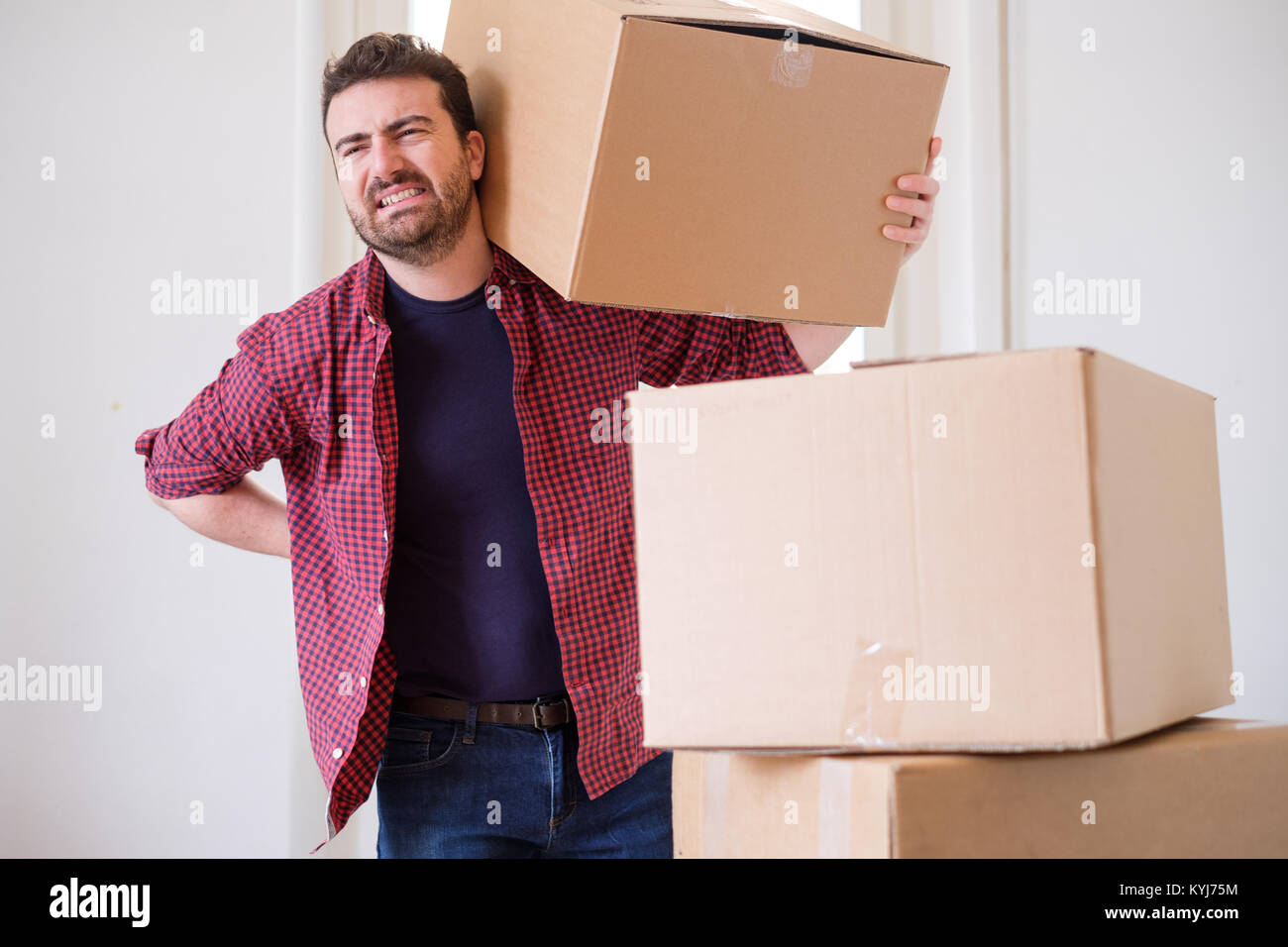 Man moving boxes and feeling back pain because heavy weight Stock Photo