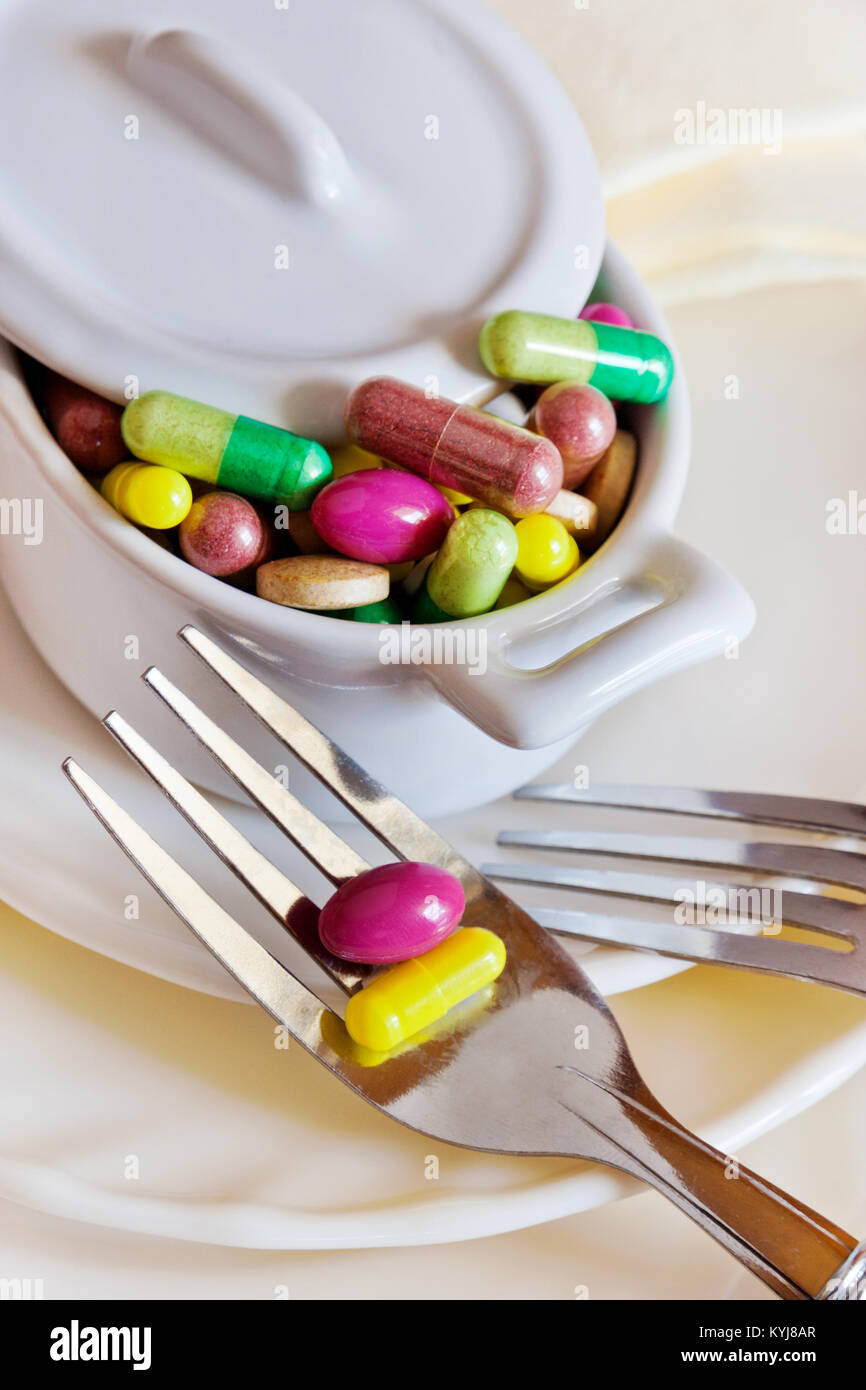 health care and wellness - diet pills and loosing weight - various tablets in a pot with forks Stock Photo