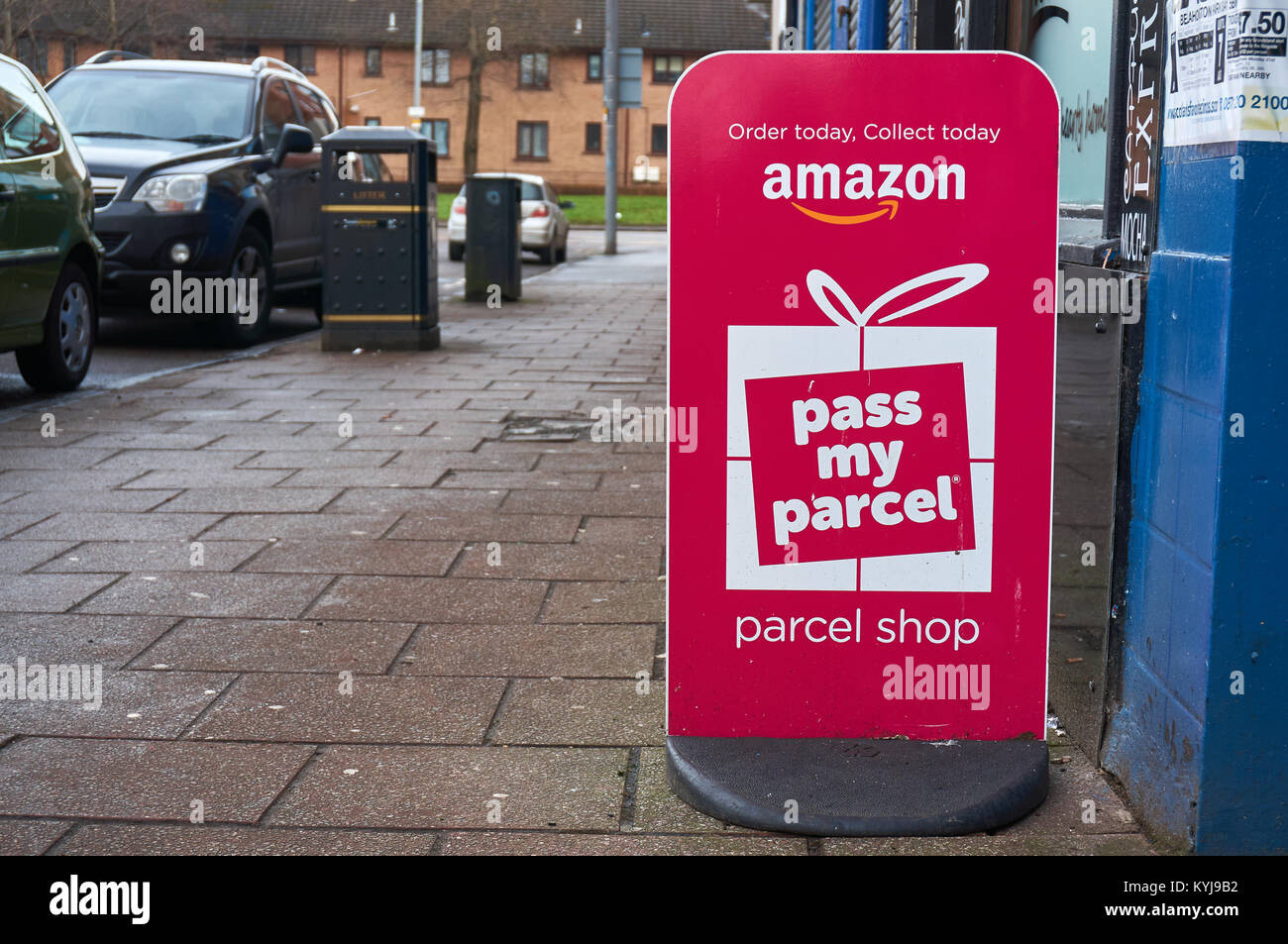 Amazon pass my parcel pink banner ad in front of a local newsagent acting as parcel shop. Stock Photo