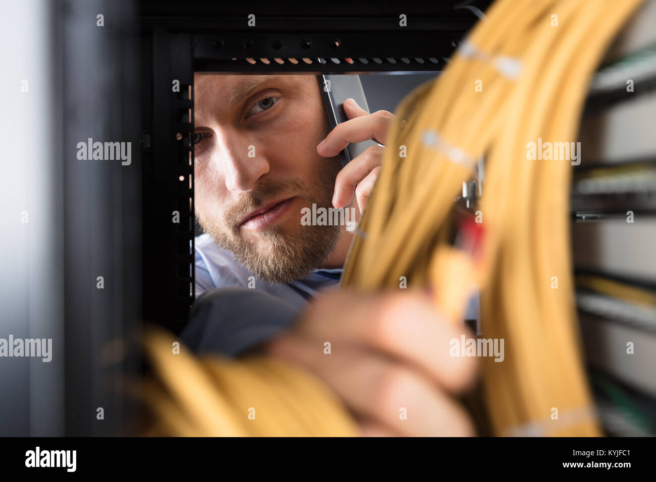 Technician Talking On Mobile Phone While Working In Server Room Stock