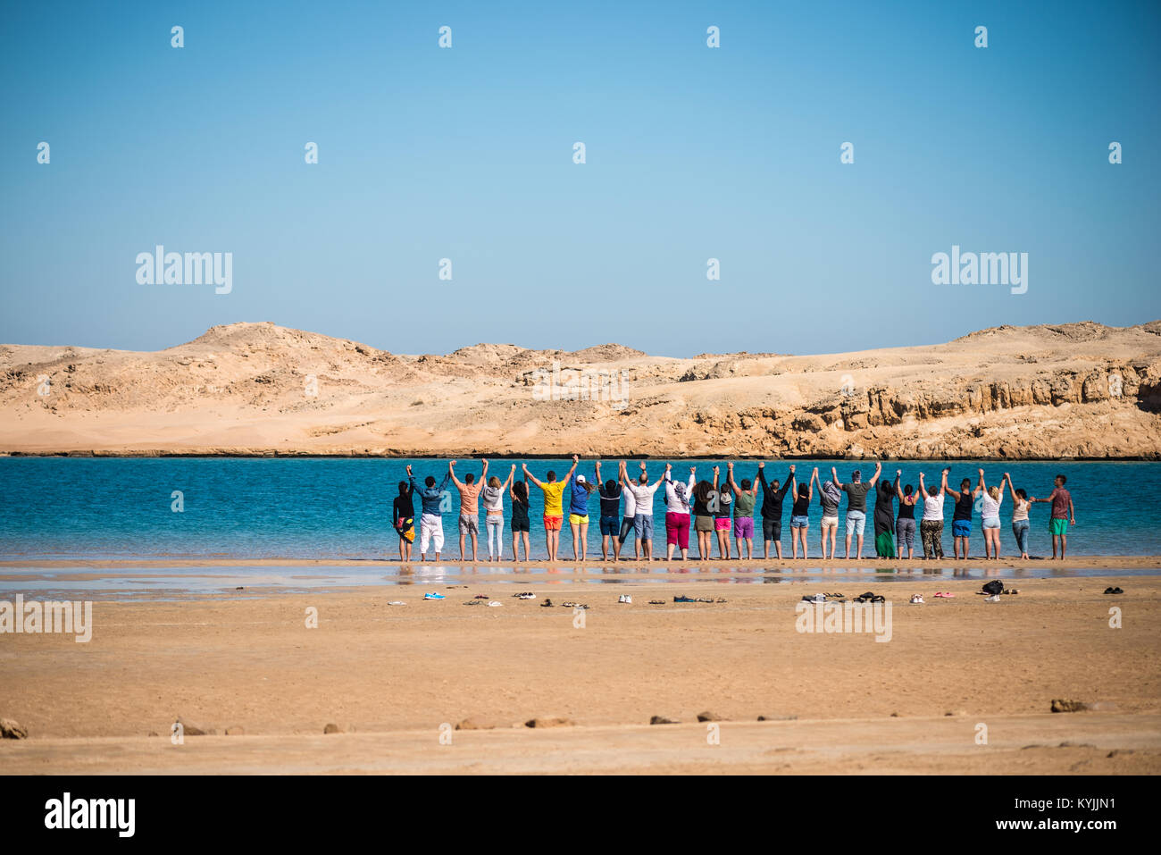 A group of people holding hands each other and standing near a blue ...