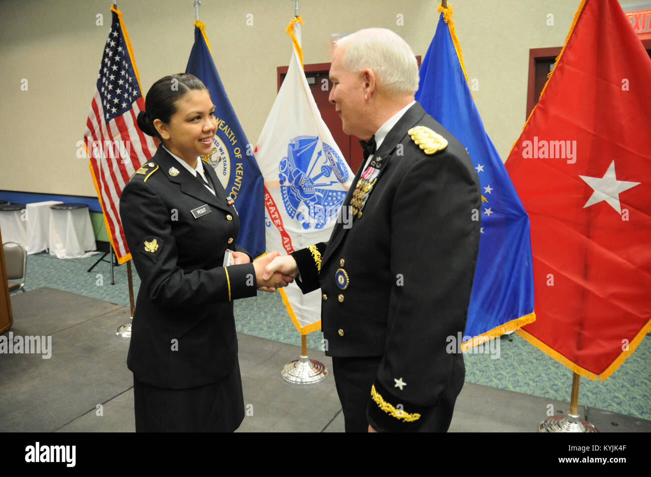 Brig. Gen. Benjamin F. Adams, chief of the Joint Staff, Joint Forces Headquarters, Kentucky National Guard, presents Spc. Stacy Pesut, human resources specalist, Headquarters and Headquarters Detachment, 103rd Chemical Battalion, with his coin for her exceptional performance of the National Anthem and &quot;My Old Kentucky Home,&quot; during the 2015 Outstanding Airman and Soldier of the Year Banquet March 14, 2015 at the Kentucky Fair and Exposition Center in Louisville, Kentucky. The annual awards dinner honors Kentucky's finest Airmen and Soldiers who are recognized by their peers for dedic Stock Photo