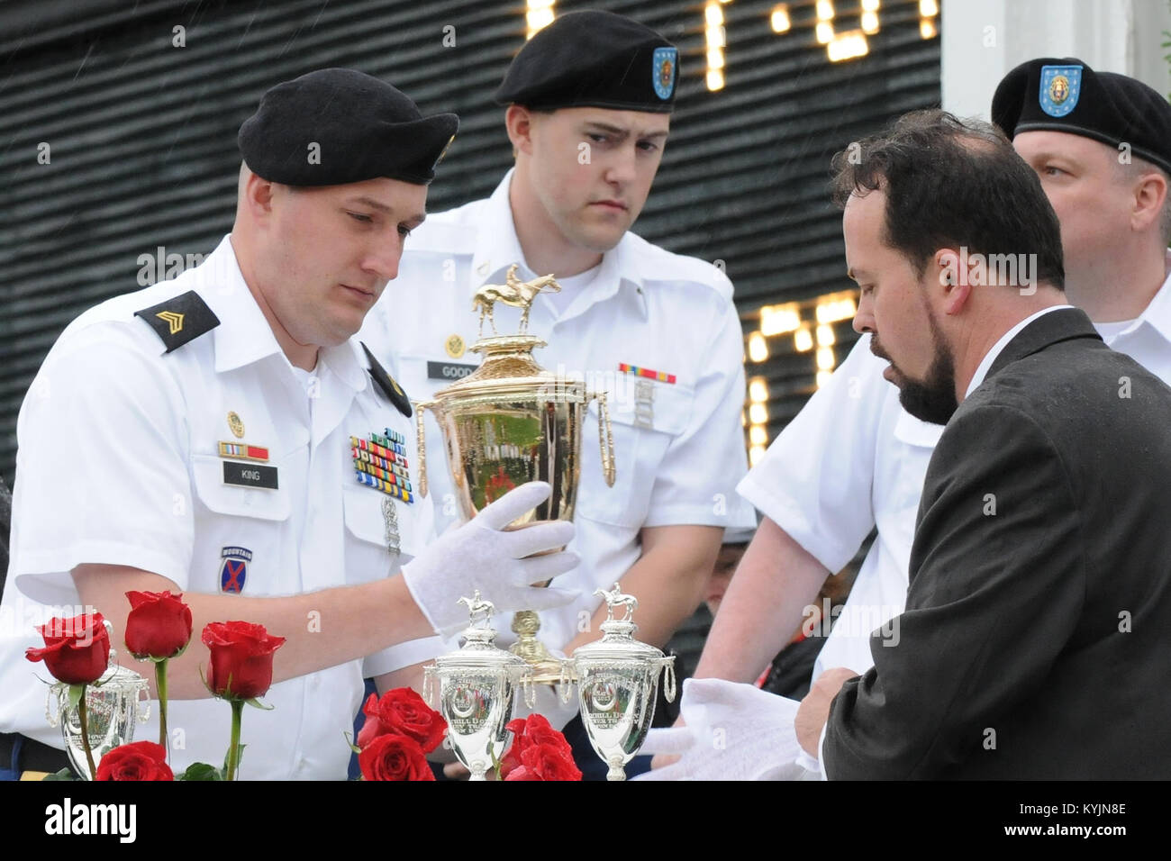 Sgt. Christopher King and Pfc. Heath Good, both of the 198th Military Police Battalion assist Kentucky Derby Museum Curator, Chris Goodlett in placing the trophies in the winner’s circle of Churchill Downs in Louisville, Ky., May 4, 2013. King and Good were two of five Soldiers chosen for the elite detail that guards the trophies from the clubhouse to the winner’s circle. (U.S. Army National Guard photo by Staff Sgt. Scott Raymond) Stock Photo