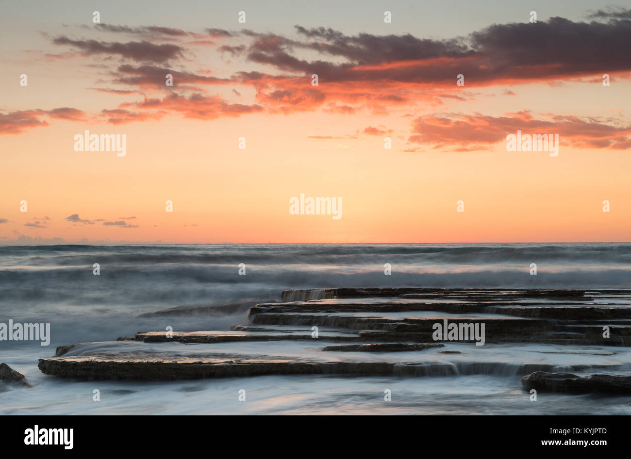 Dramatic beautiful sunset on a rocky coast. Long exposure photography Stock Photo