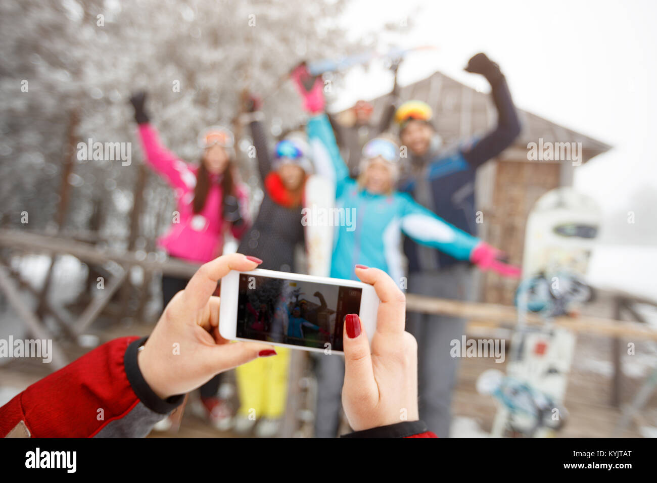 Close up of hands making photo of cheerful skiers with cell phone Stock Photo