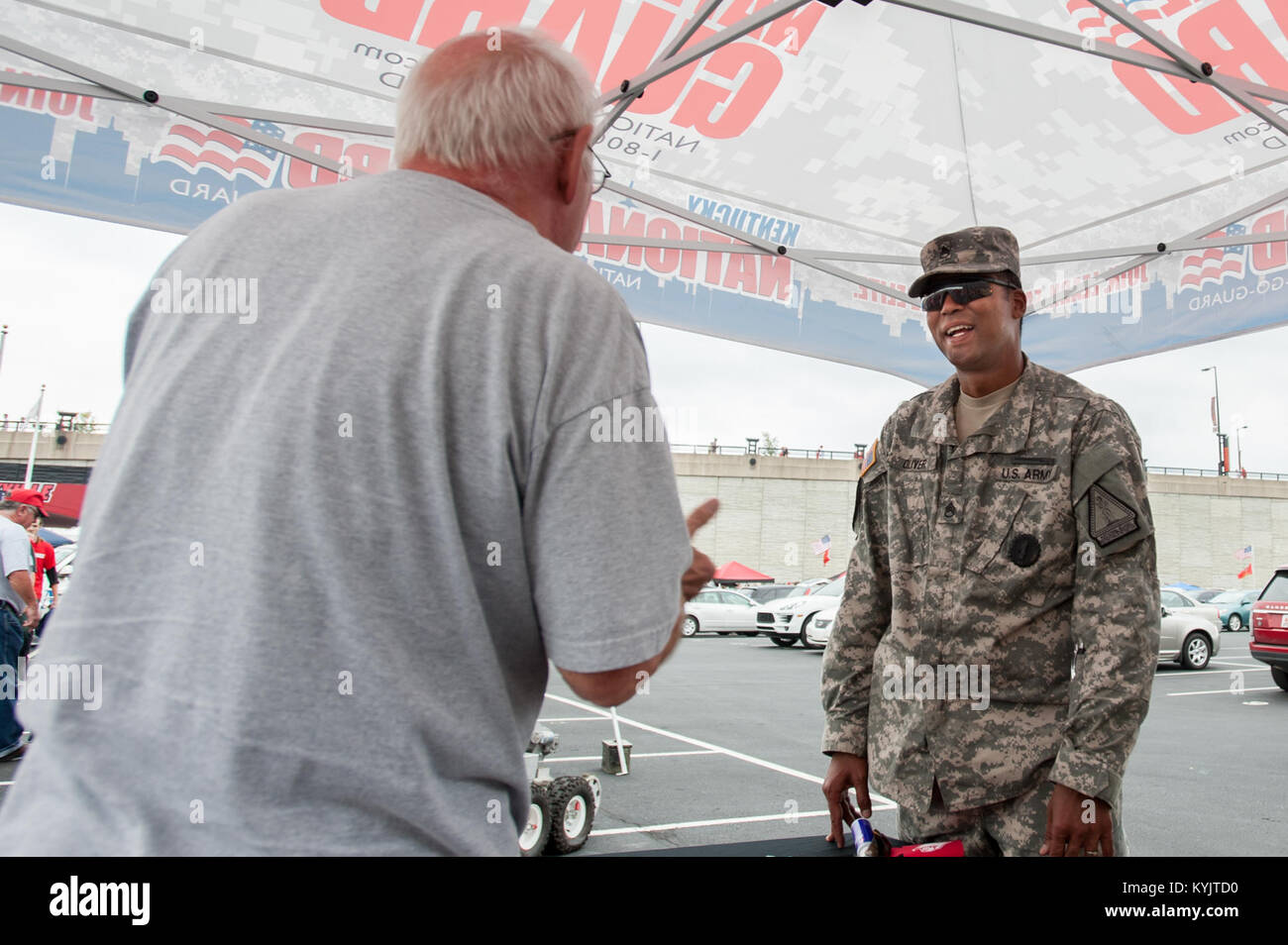 Army Staff Sgt. Michael Oliver, a recruiter for the Kentucky Army National Guard, speaks with a football fan outside Papa John’s Cardinal Stadium in Louisville, Ky., prior to the University of Louisville – Murray State football game Sept. 6, 2014. The game, billed as Military Appreciation Day, began with a coin toss executed by Air Force Brig. Gen. Warren Hurst, the Kentucky National Guard's assistant adjutant general for Air and commander of the Kentucky Air National Guard. (U.S. Air National Guard photo by Maj. Dale Greer/Released) Stock Photo