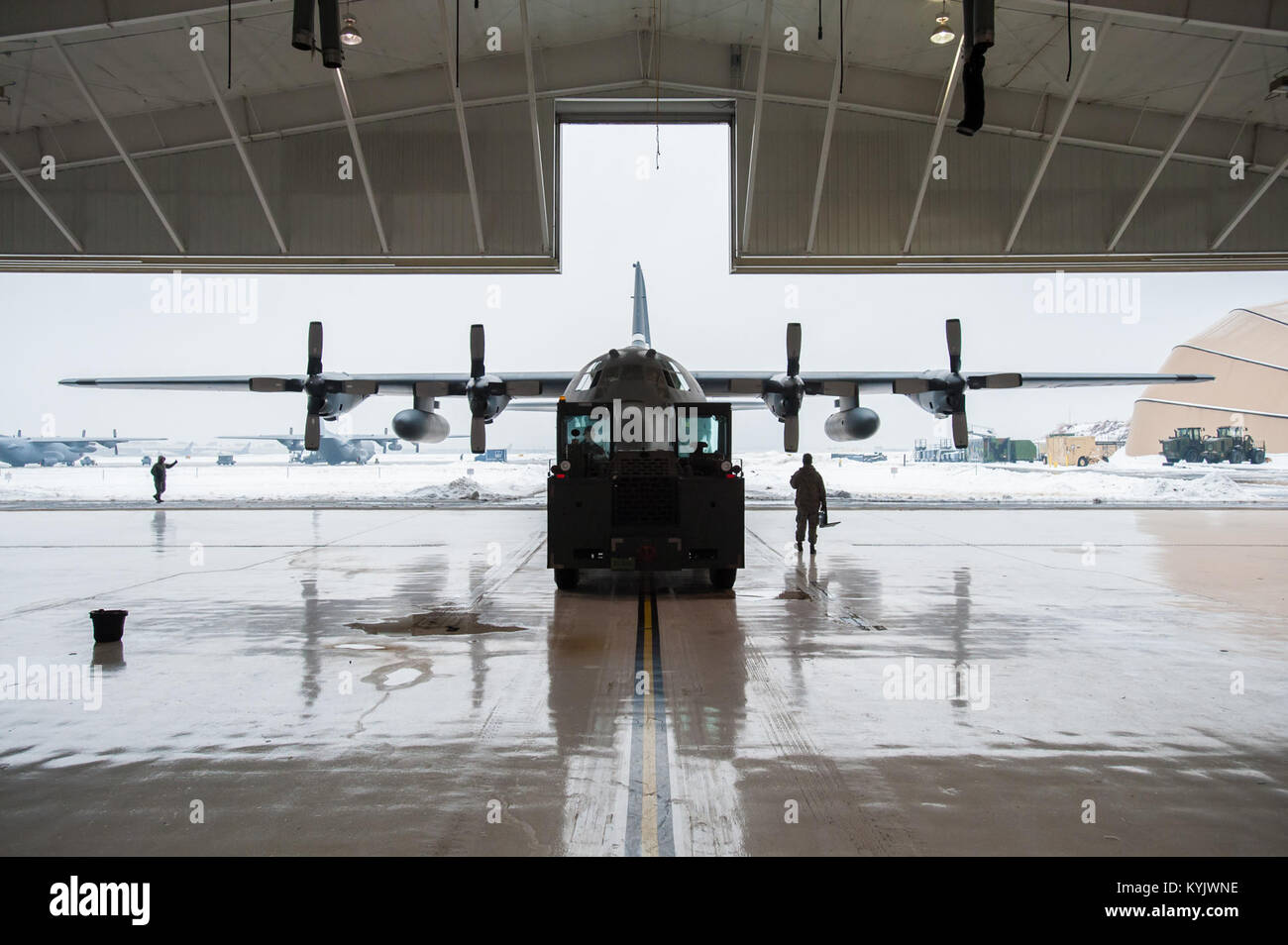Members of the 123rd Aircraft Maintenance Squadron push a C-130 Hercules aircraft from a hangar at the Kentucky Air National Guard Base in Louisville, Ky., Feb. 21, 2015. The aircraft, which subsequently departed for the Persian Gulf along with 37 deploying Kentucky Air Guardsmen, was being housed in the hangar because of severe weather conditions. (U.S. Air National Guard photo by Maj. Dale Greer) Stock Photo
